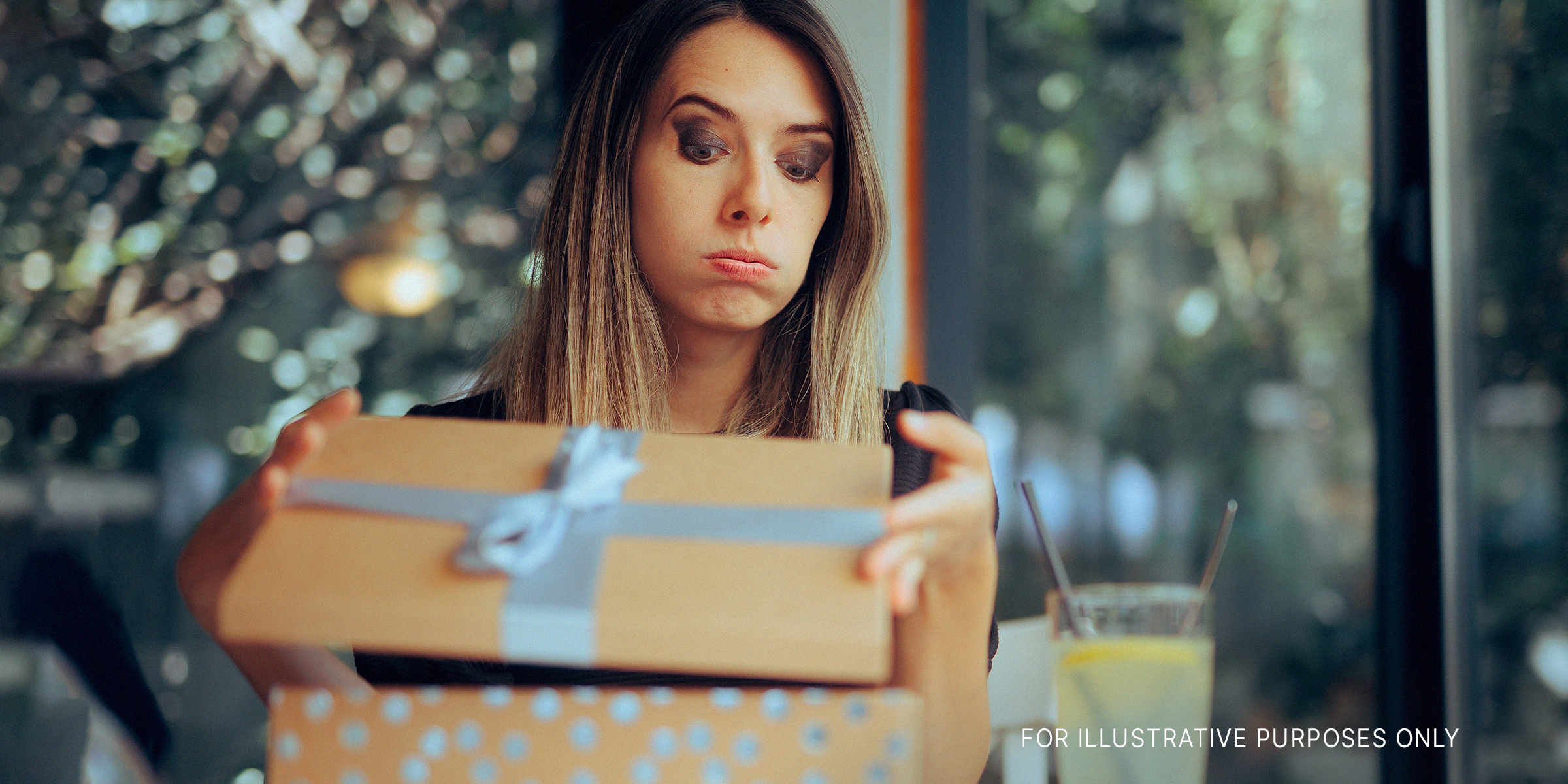A skeptical woman opening a gift | Source: Shutterstock