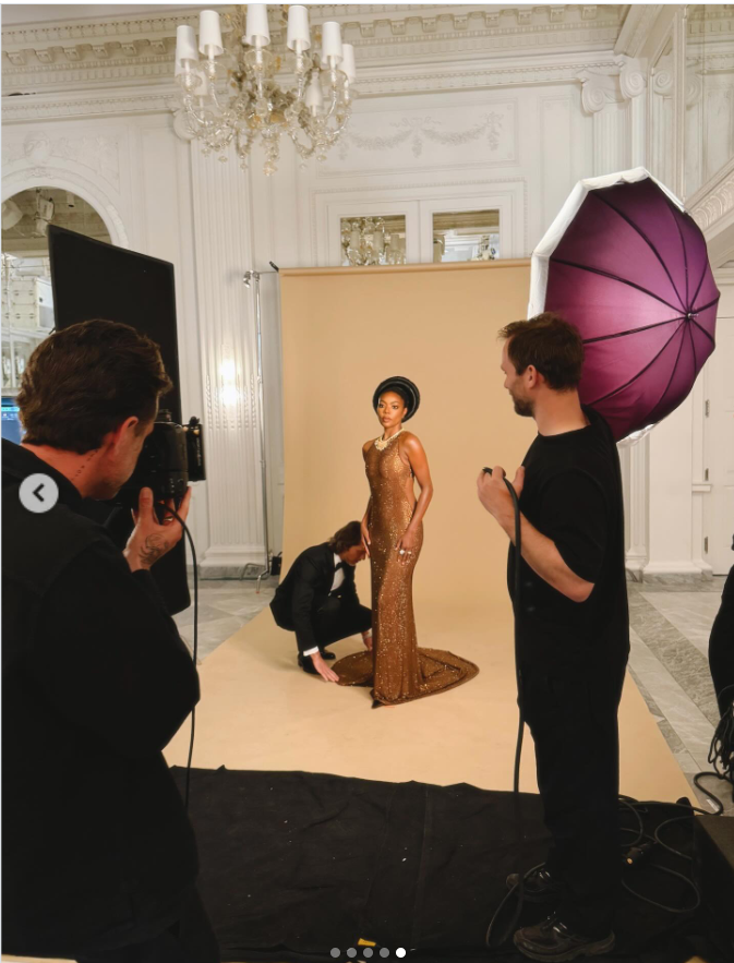 Gabrielle Union poses in a studio setting wearing the same shimmering bronze gown with a long, elegant train. Stylists adjust the fabric around her as soft lighting highlights the gown's texture and glow. | Source: Instagram/gabunion