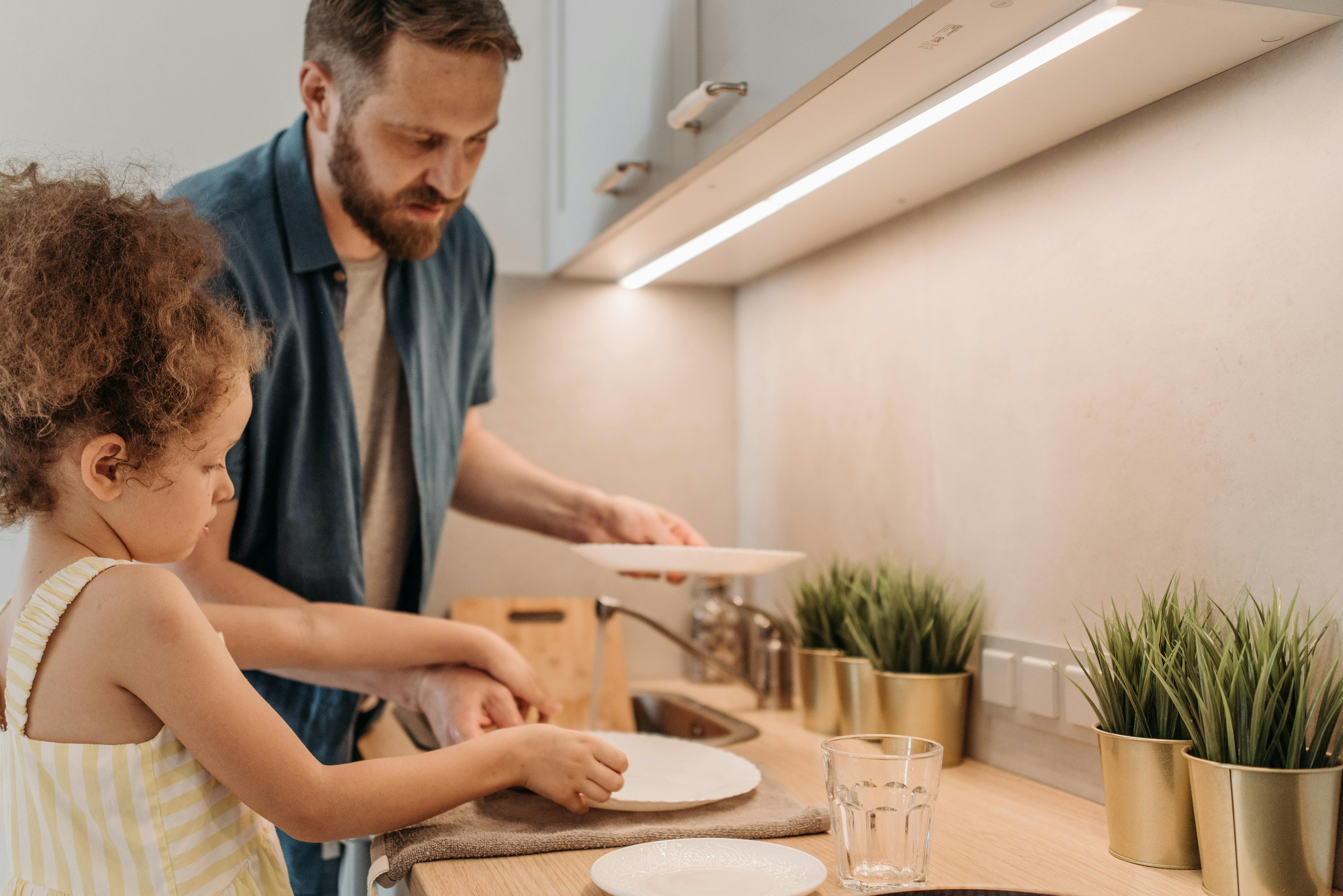 A man washing dishes with his daughter | Source: Pexels