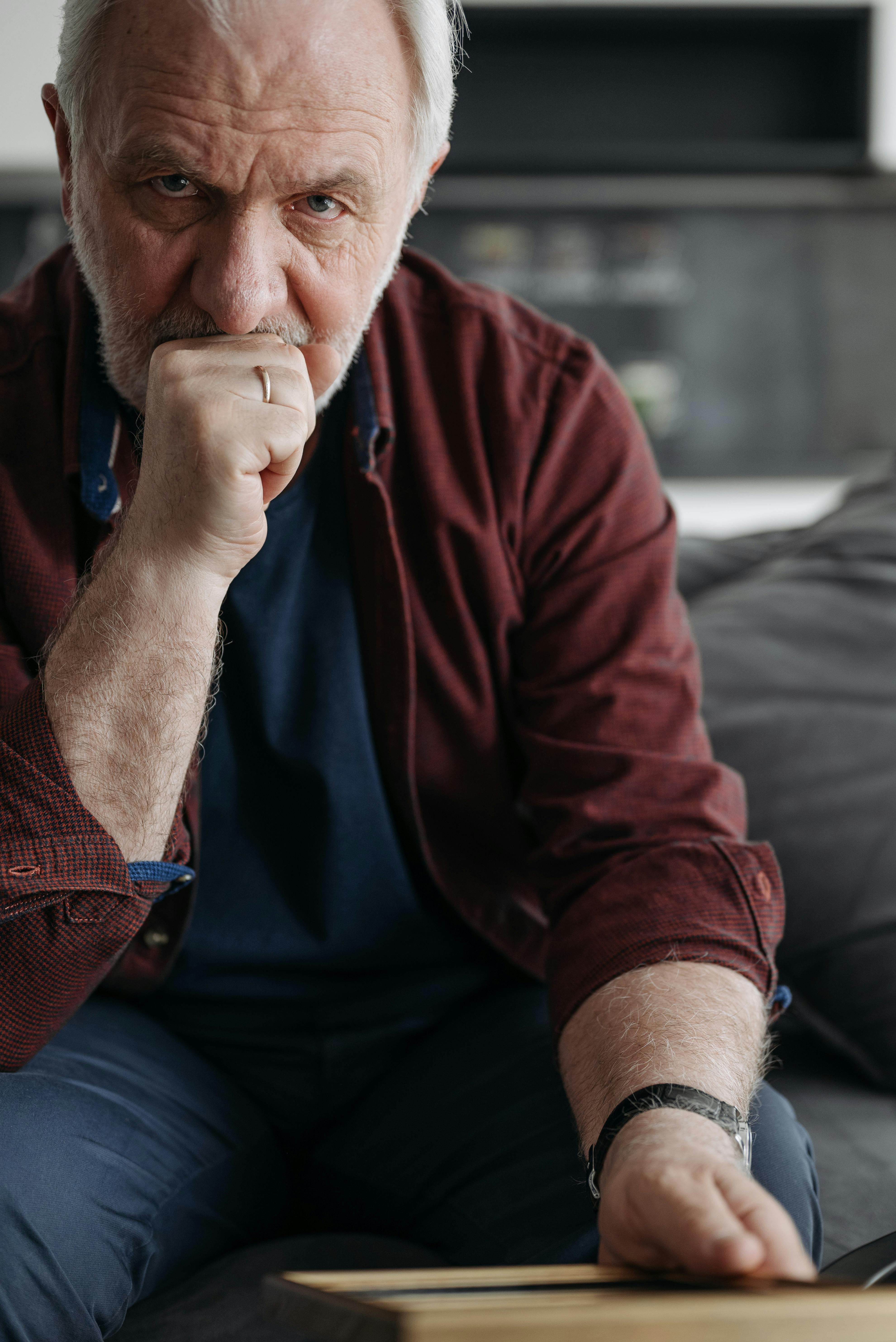 An unhappy-looking man sitting on a couch | Source: Pexels