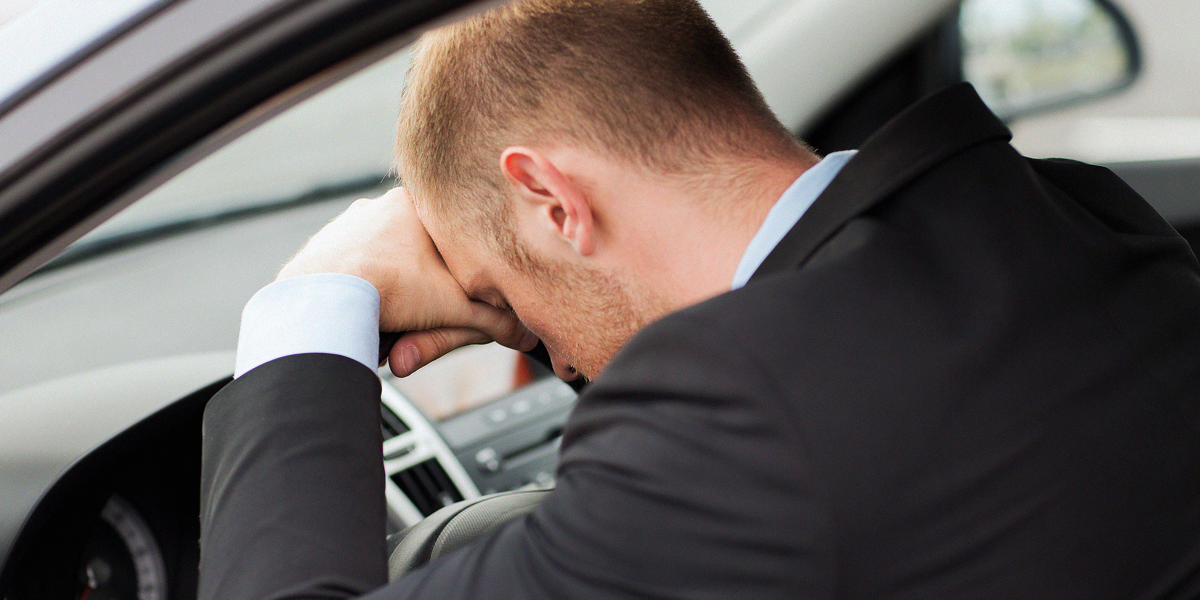Man sitting in car with his head on the steering wheel | Source: Shutterstock
