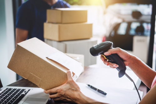 A postal worker scanning a package. | Source: Shutterstock. A postal worker scanning a package. | Source: Shutterstock.