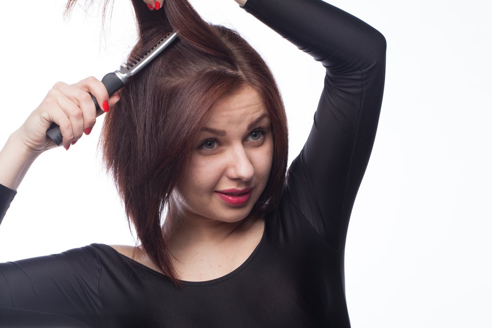 Mujer dividiendo su cabello en seccciones. | Foto: Shutterstock