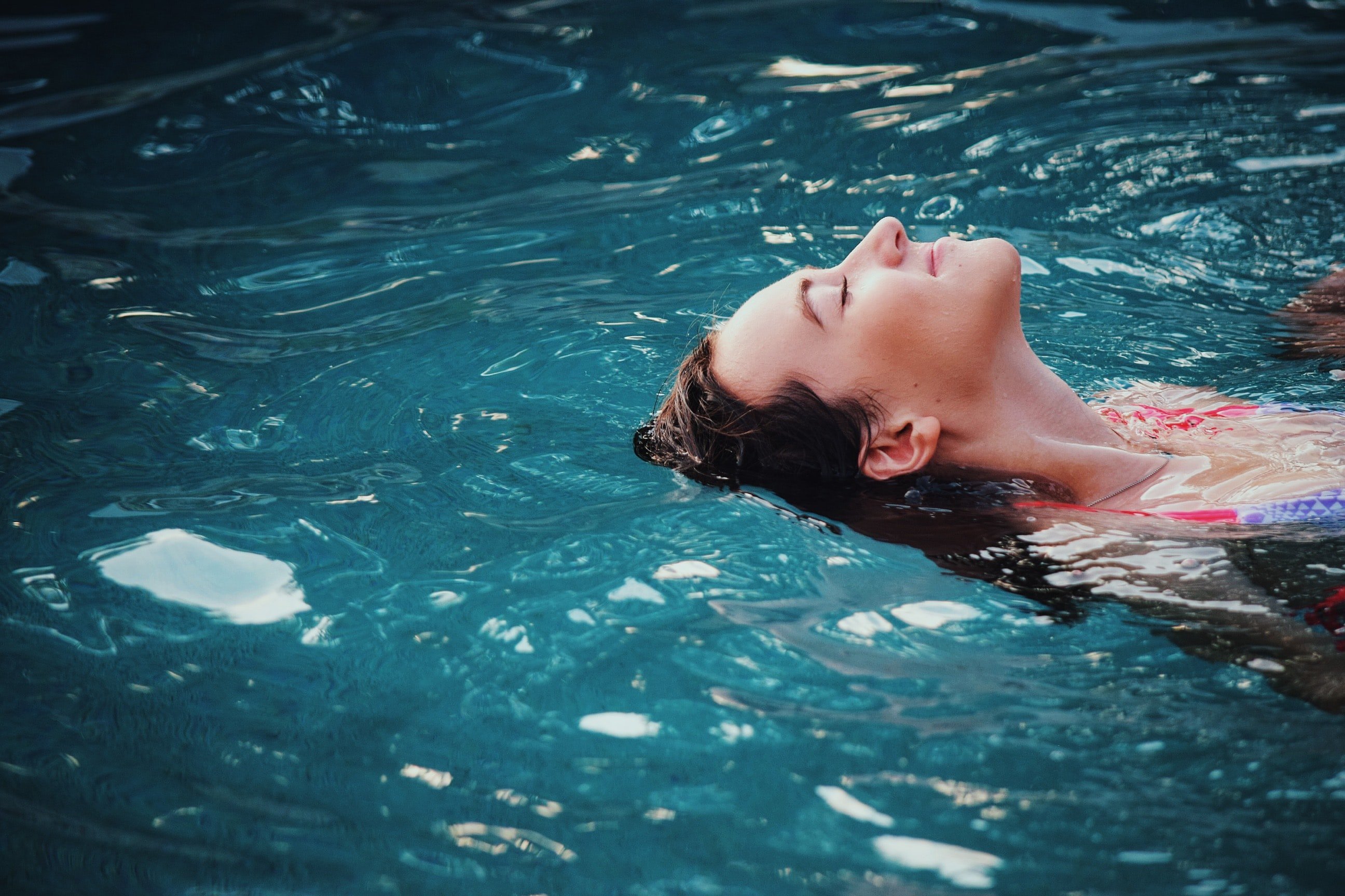 Woman floating in pool | Unsplash 