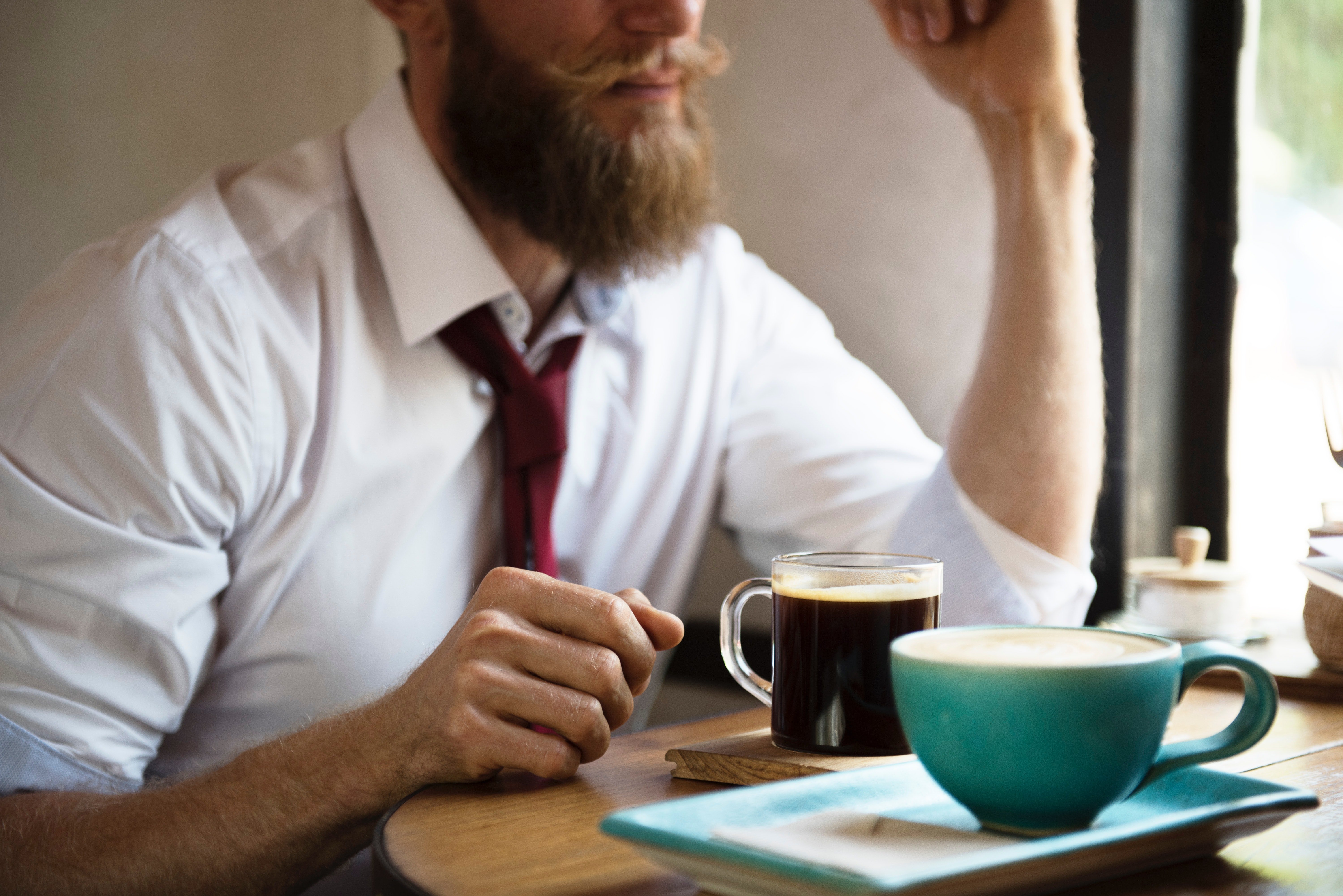 Man sitting at a table with a hot drink. | Source: rawpixel.com/Pexels