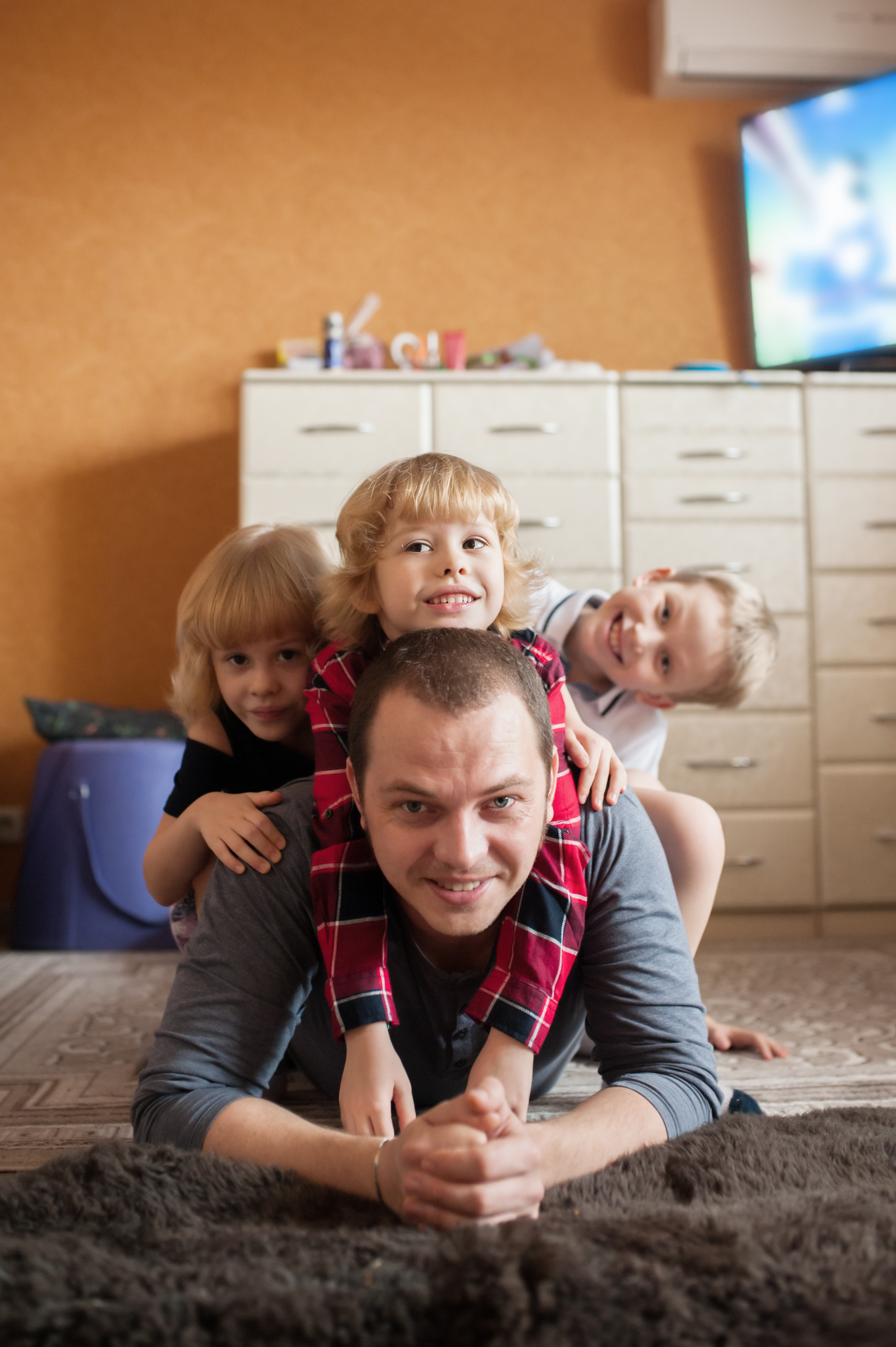 A father lying on the floor with his children riding on his back | Source: Shutterstock