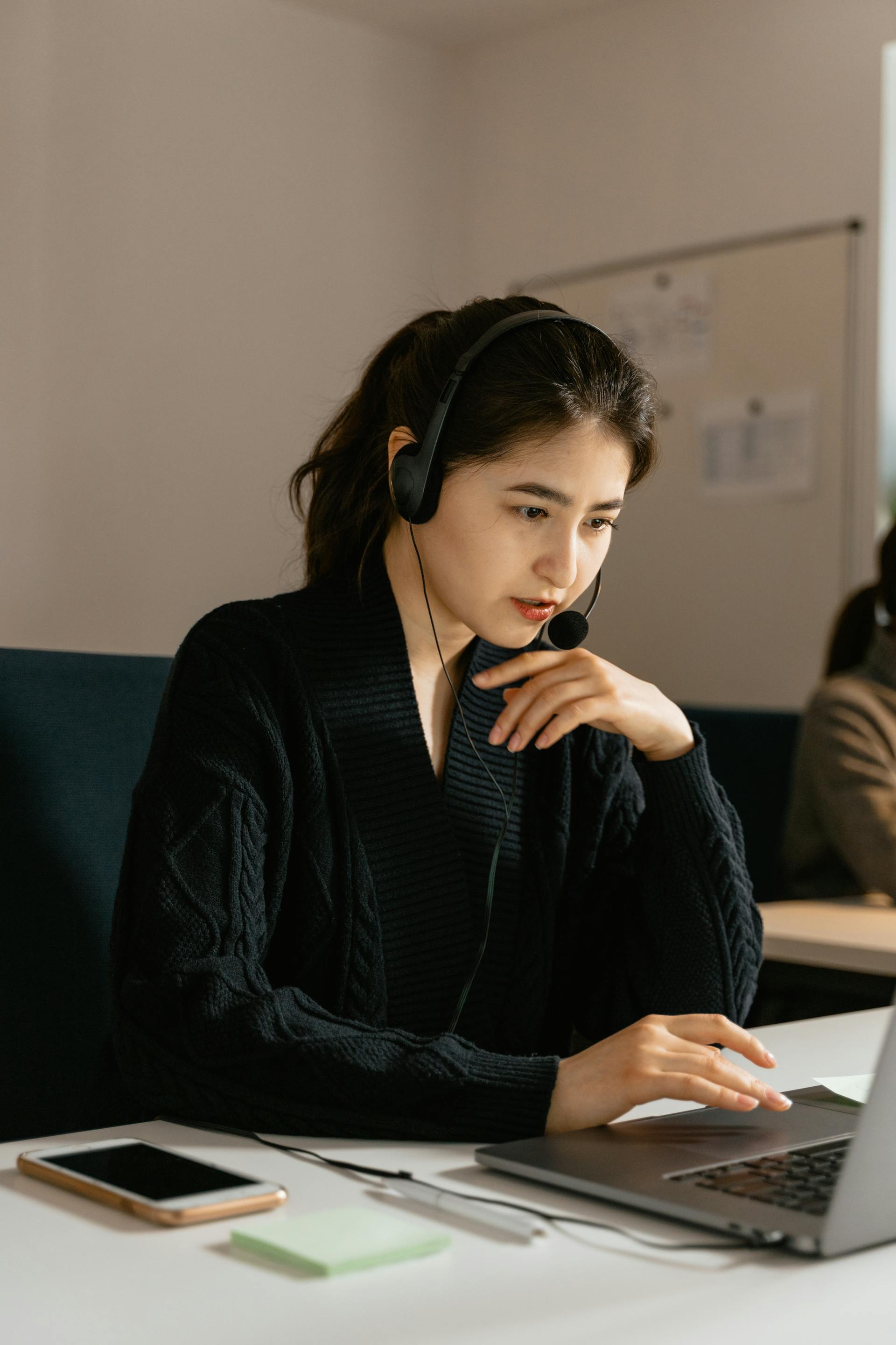 A woman with a headset and mouthpiece sitting in front of a laptop | Source: Pexels