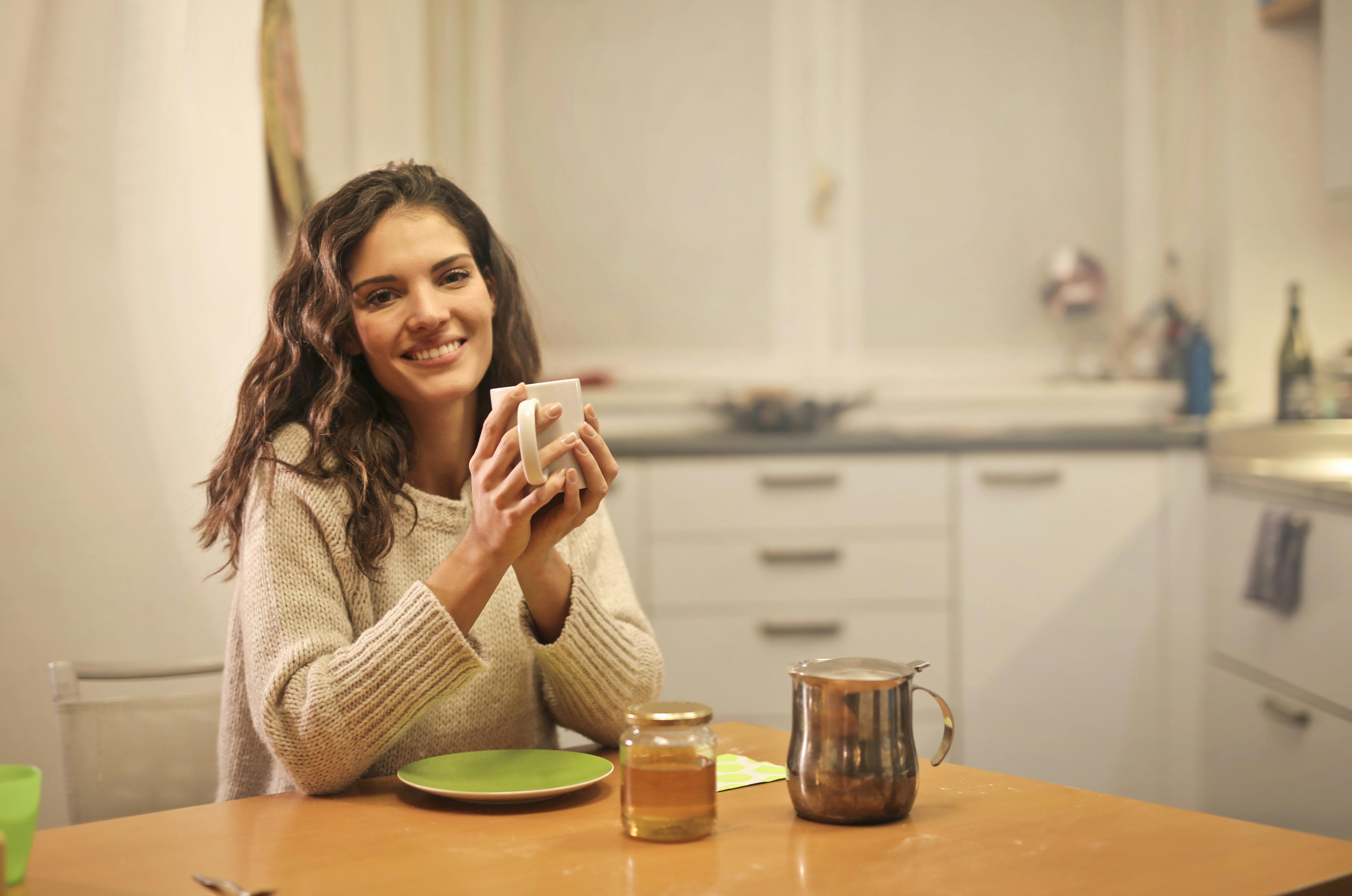 A woman smiling while holding a mug | Source: Pexels
