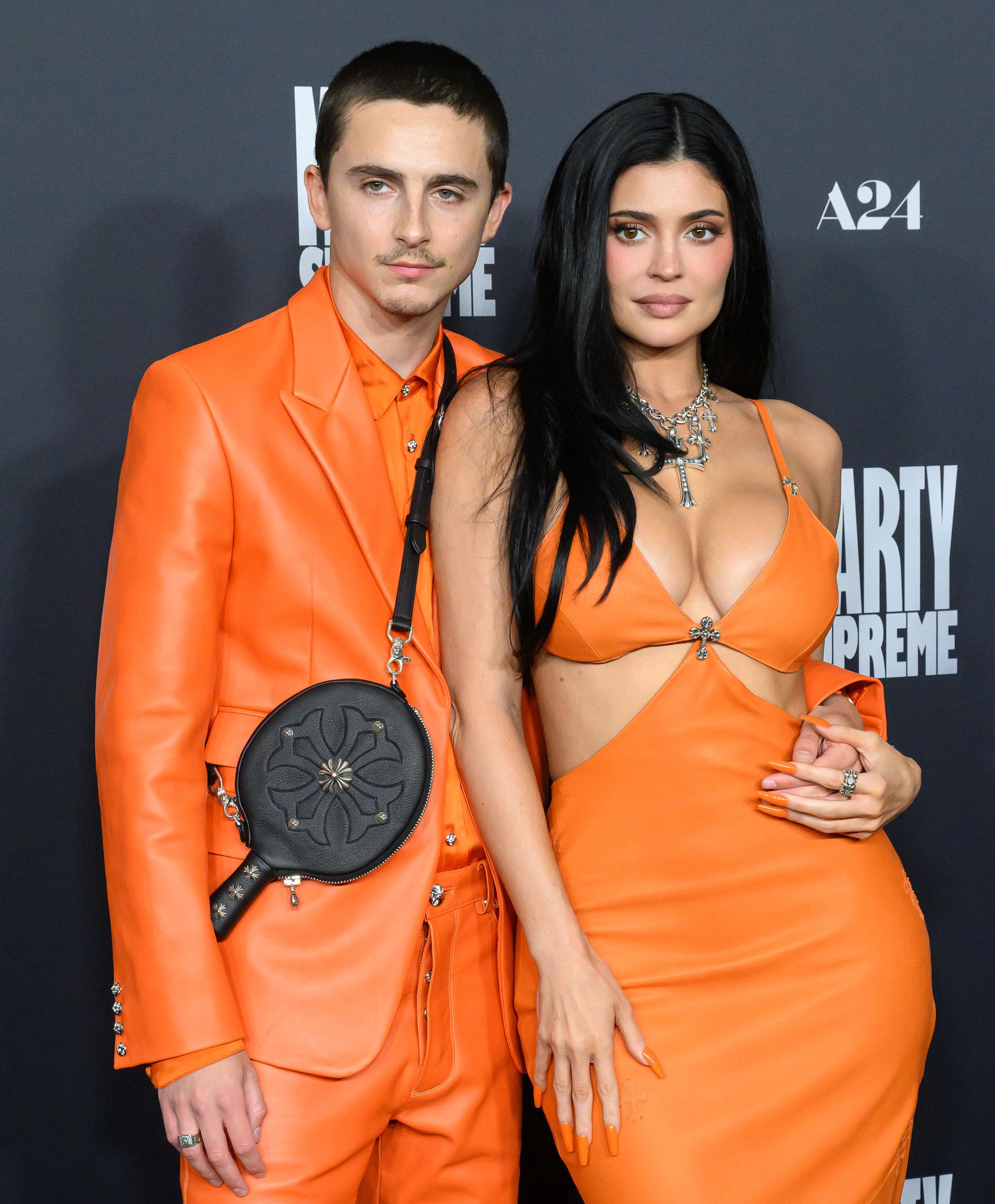 Timothée Chalamet and Kylie Jenner pose together in coordinated orange outfits at the A24 premiere of "Marty Supreme" on December 8, 2025 | Source: Getty Images