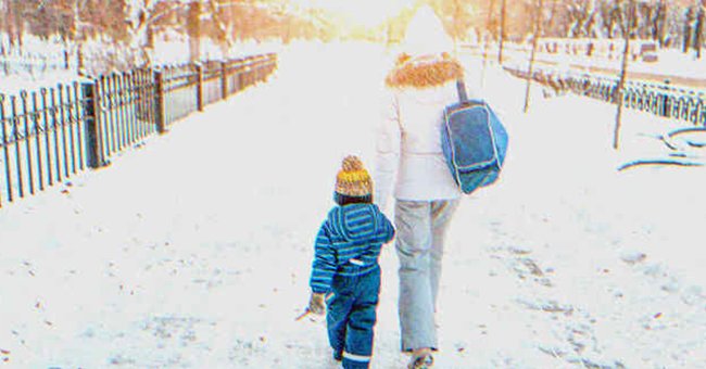 Una mujer y un niño caminando en una vía nevada tomados de la mano. | Foto: Shutterstock