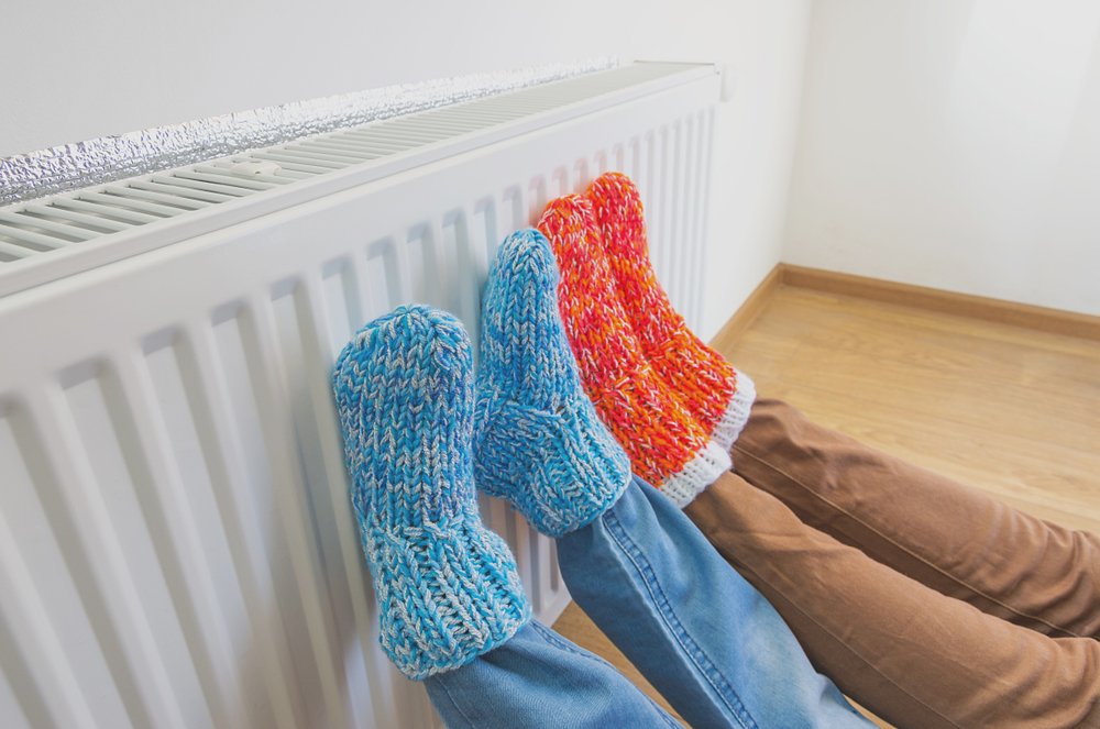 Personas calentando sus pies frente al radiador.  | Foto: Shutterstock
