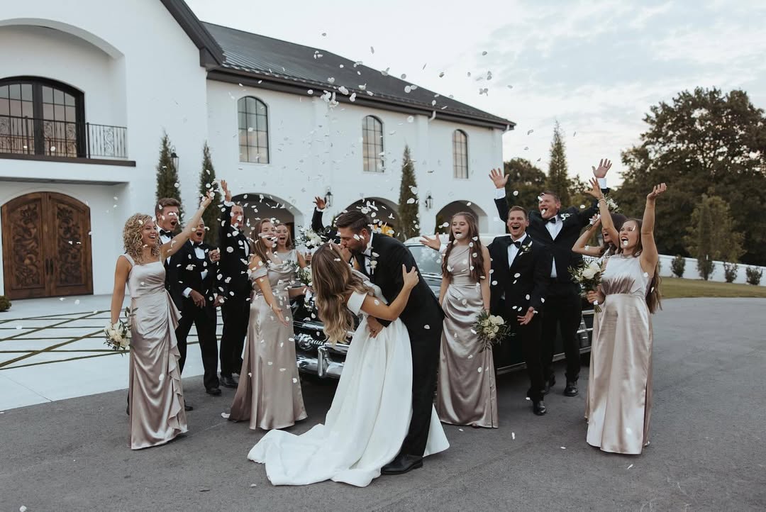 Surrounded by cheering bridesmaids and groomsmen, Jana Duggar and Stephen Wissmann share a kiss as flower petals rain down outside their venue. | Source: Instagram/janamduggar