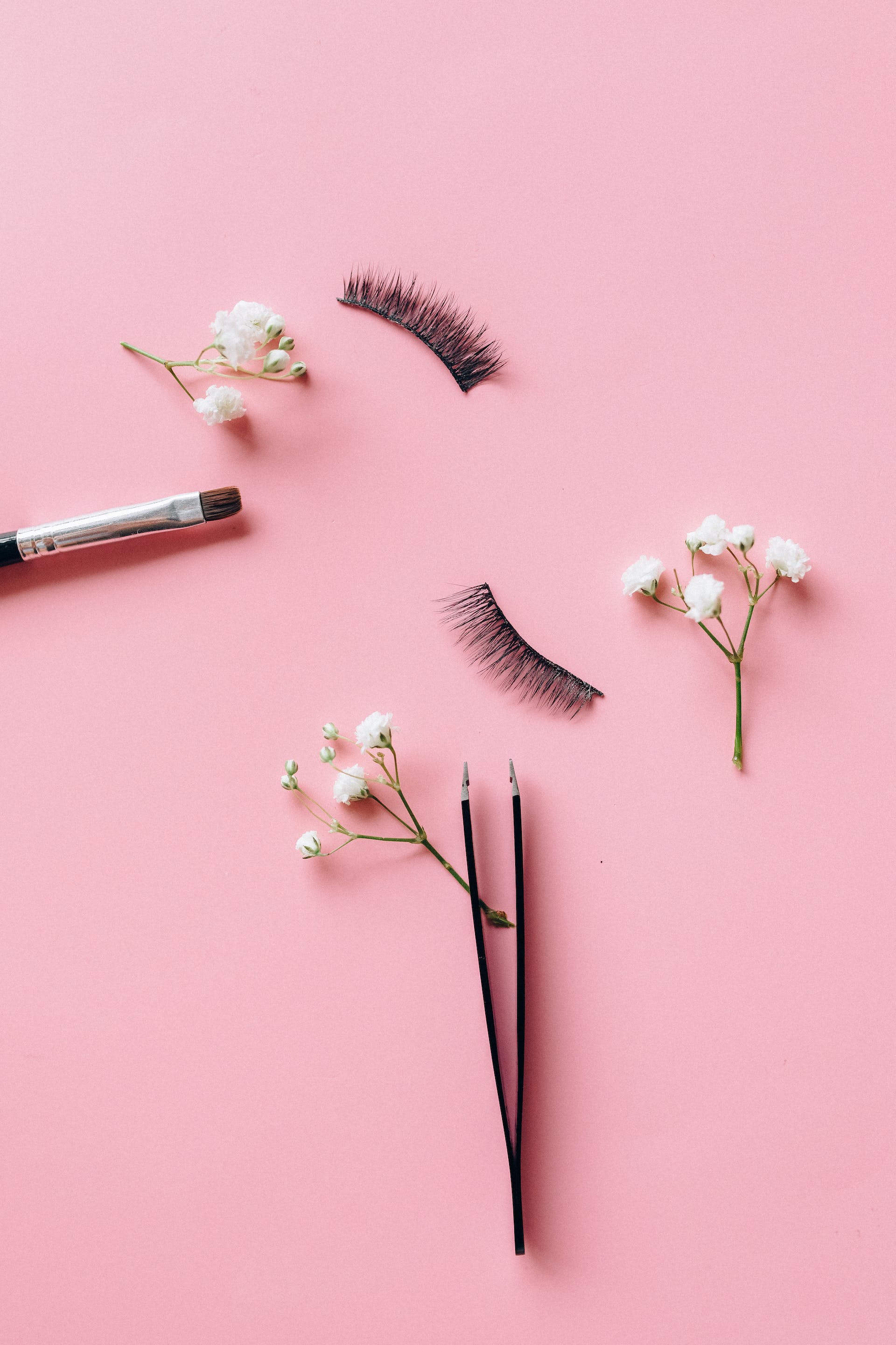 A pair of false eyelashes on a pink surface | Source: Pexels