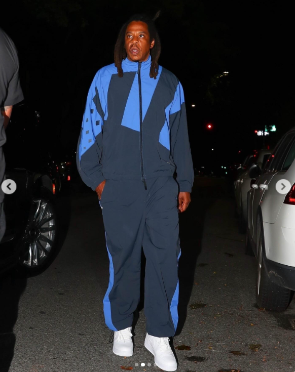 Jay-Z wears a tracksuit with blue accents and white sneakers during a date night with his wife, Beyoncé, in Brooklyn, New York, posted in August 2024 | Source: Instagram/justjared