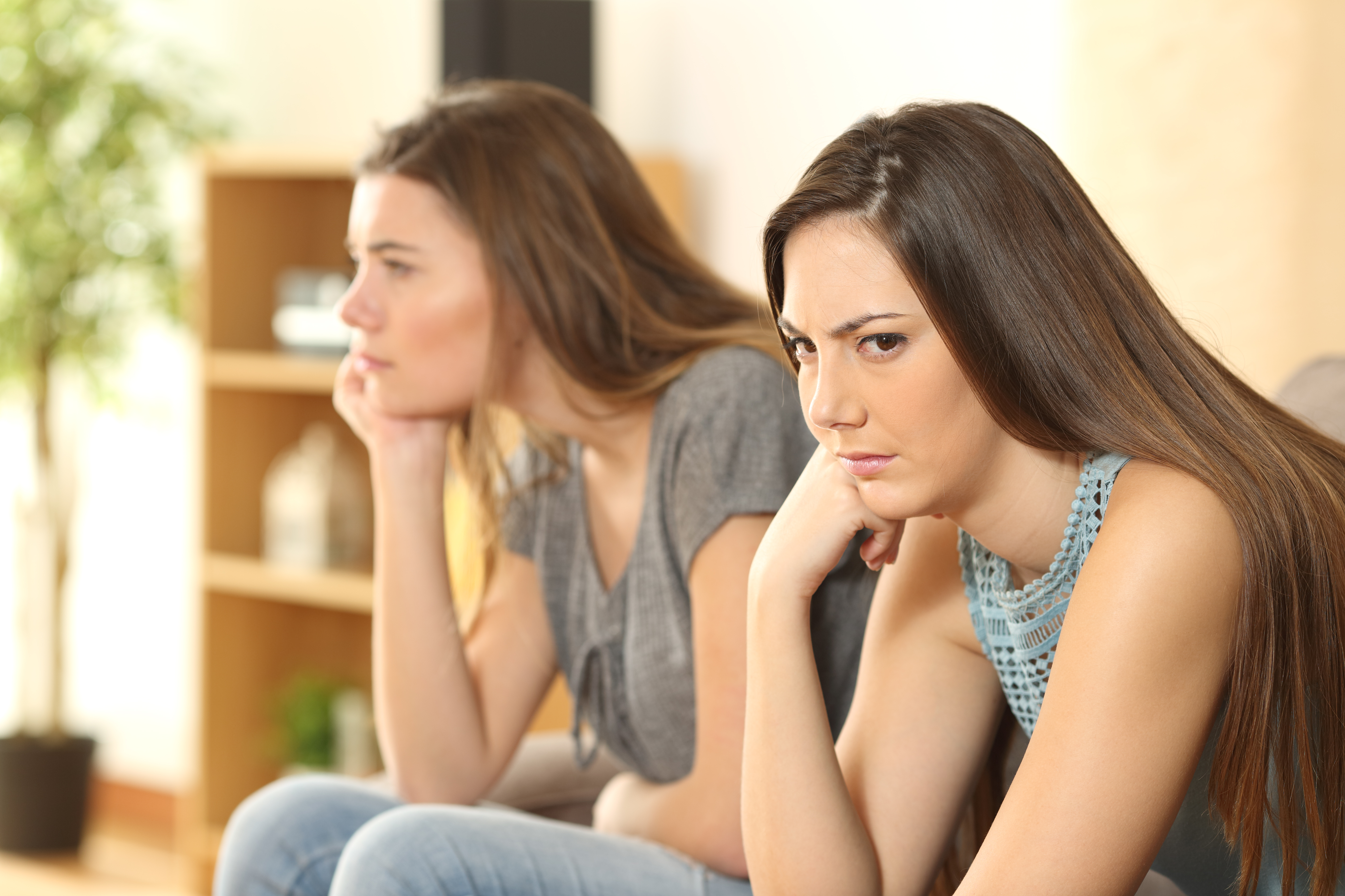 Two sisters sitting on a sofa, not talking | Source: Shutterstock