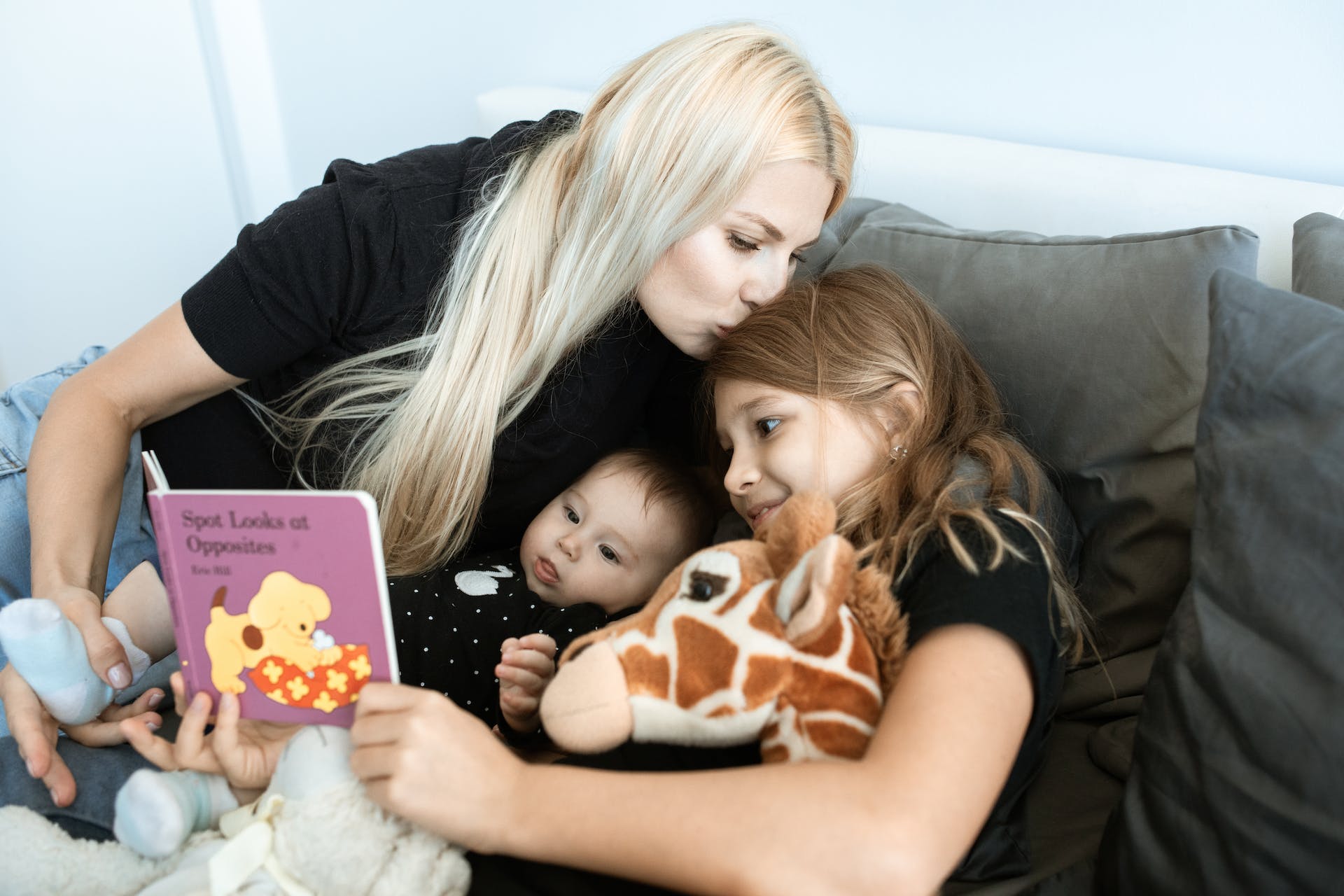 A woman bonding with her two children by reading them book | Source: Pexels