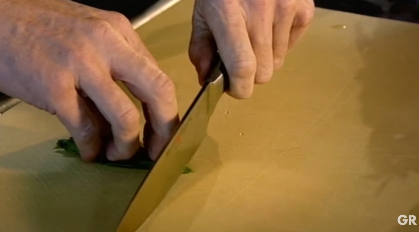Gordon Ramsay demonstrates the proper way to slice delicate herbs in a cooking tips video published on April 26, 2016. He explains that gently rolling basil leaves before using a sharp knife helps preserve their flavor by preventing the leaves from being bruised. | Source: YouTube/ Gordon Ramsay