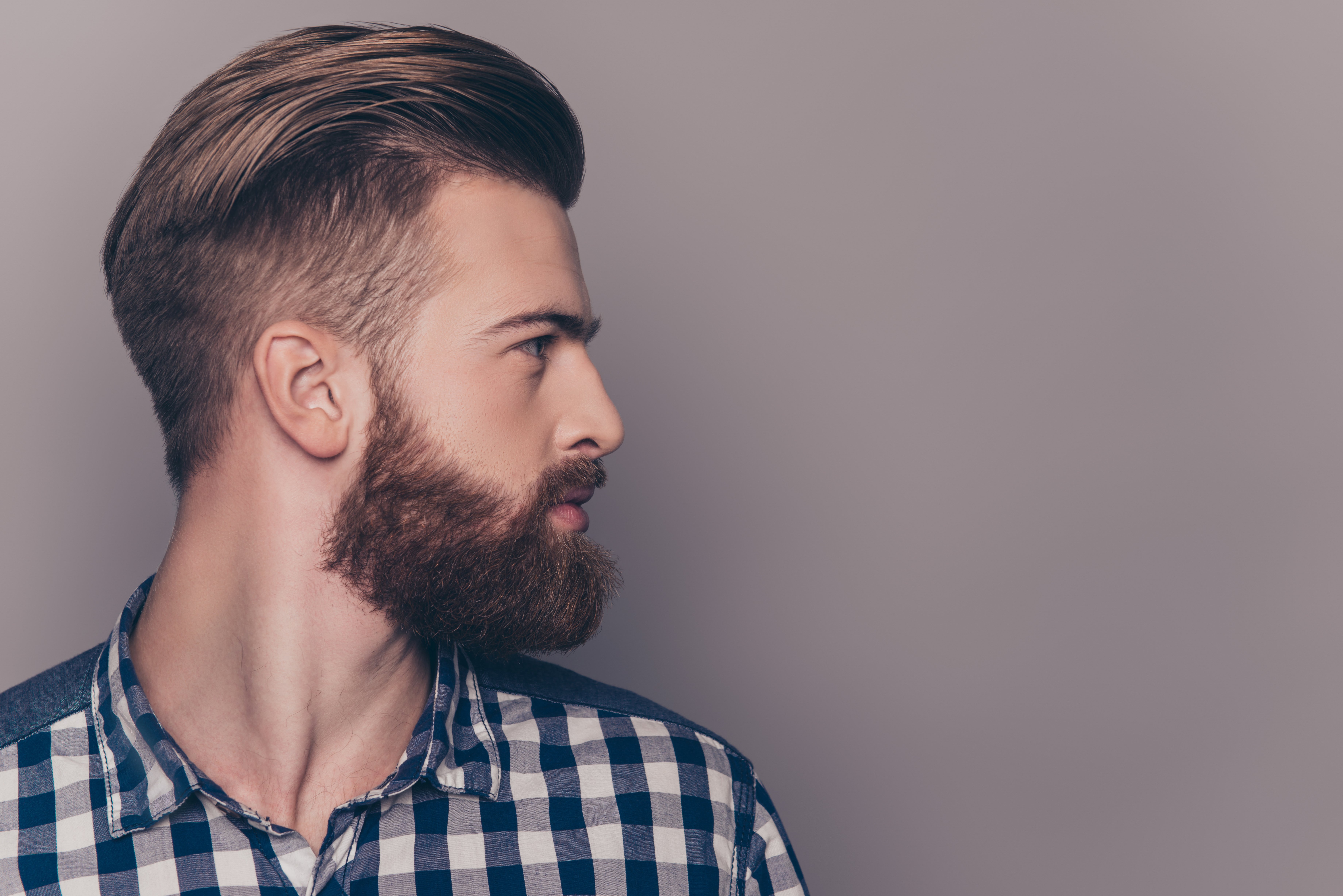 The profile of a man with a beard, wearing a blue plaid t-shirt. | Photo: Shutterstock