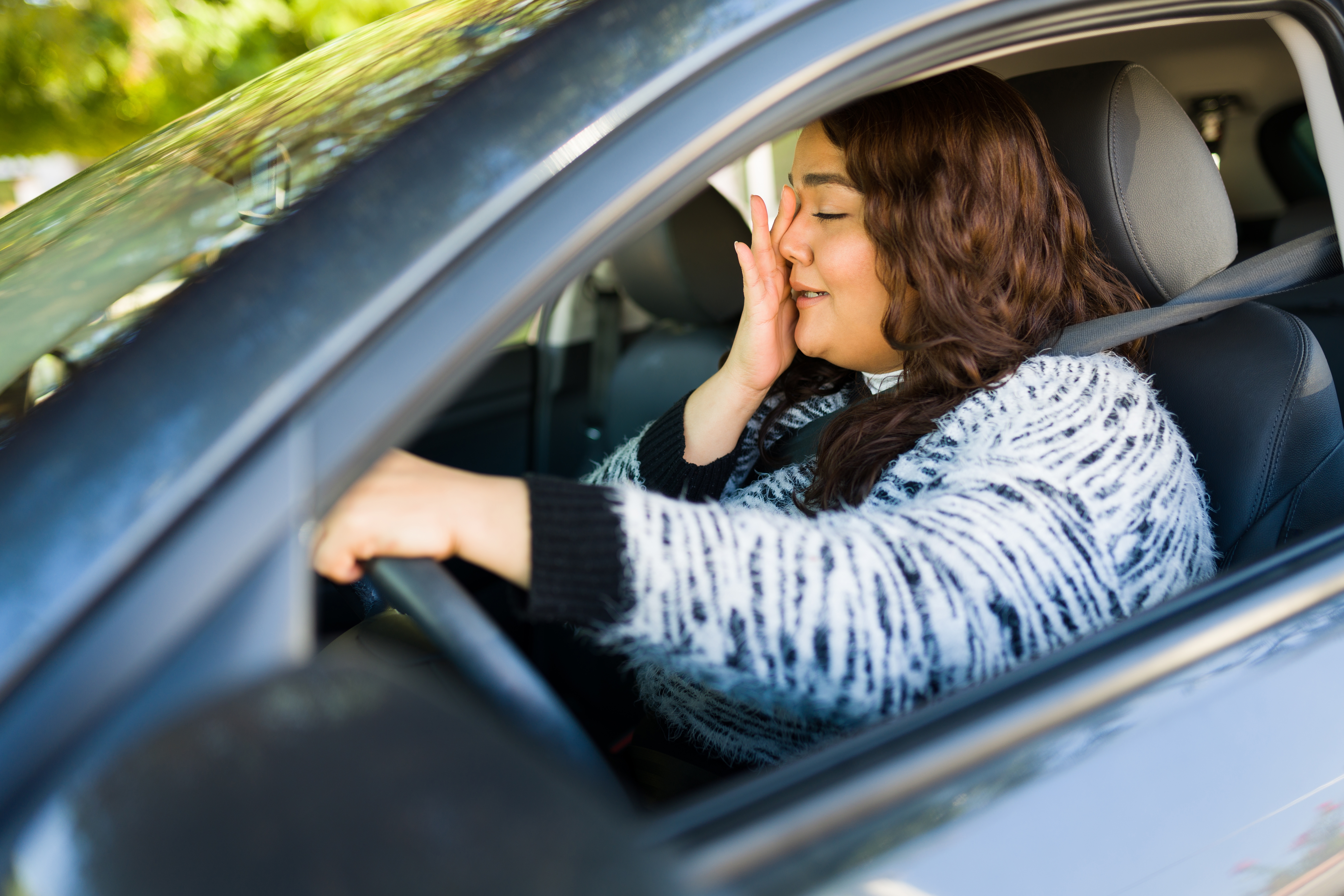 A woman crying while driving a car | Source: Shutterstock