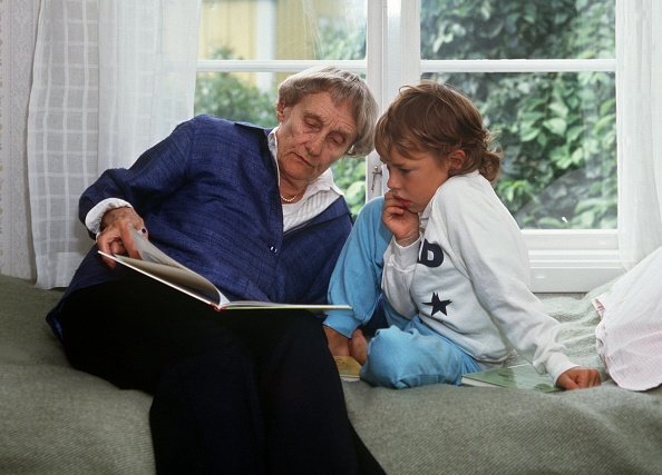 Die schwedische Kinderbuchautorin Astrid Lindgren liest im Juli 1987 einem Nachbarkind in ihrem Haus am Furusund in der Nähe von Stockholm aus einem Buch vor | Quelle: Getty Images