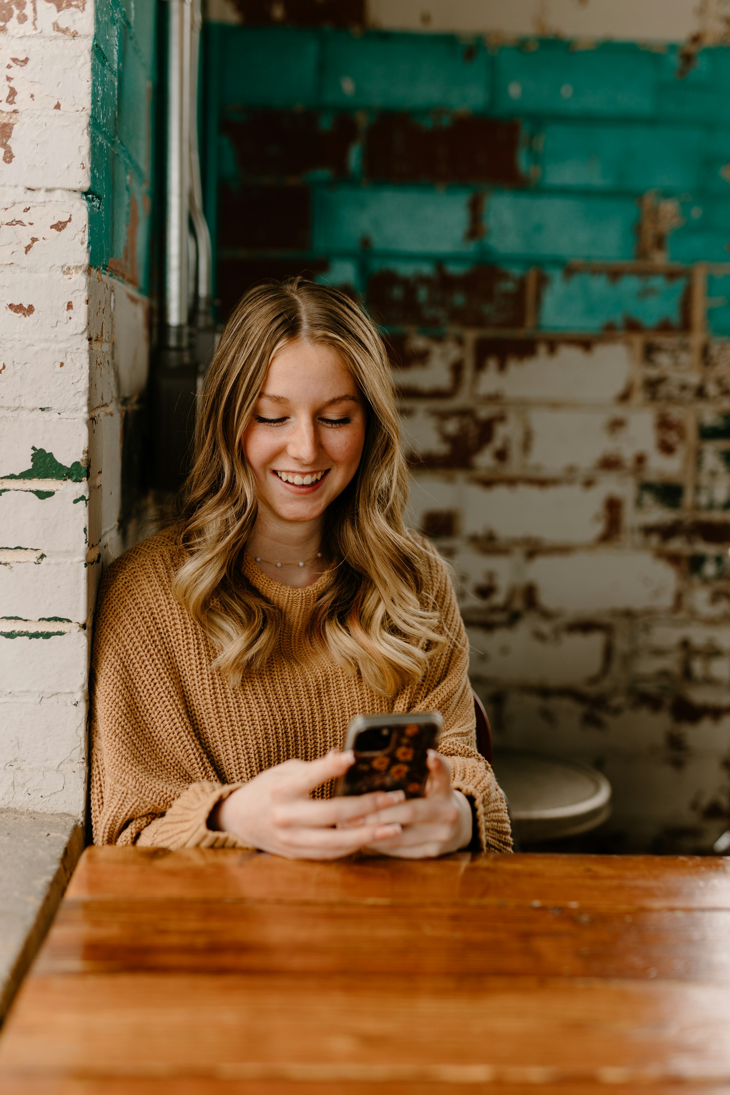 A woman smiling while texting on her phone | Source: Unsplash