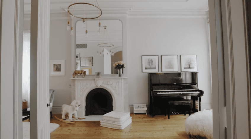 The parlor floor has a family room with a piano and fireplace | Source: YouTube/Architectural Digest