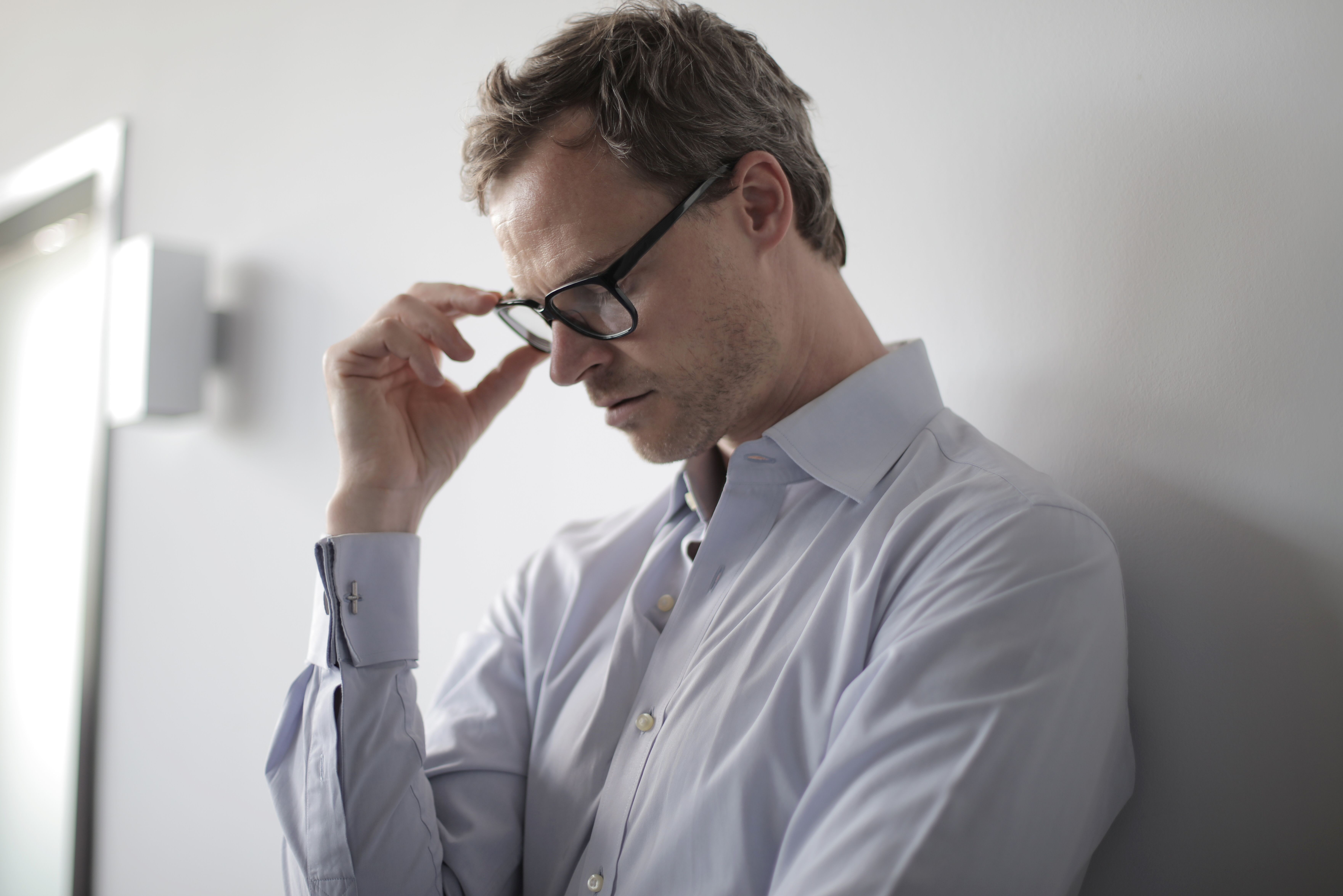 A man leaning against a wall with his head down | Source: Pexels