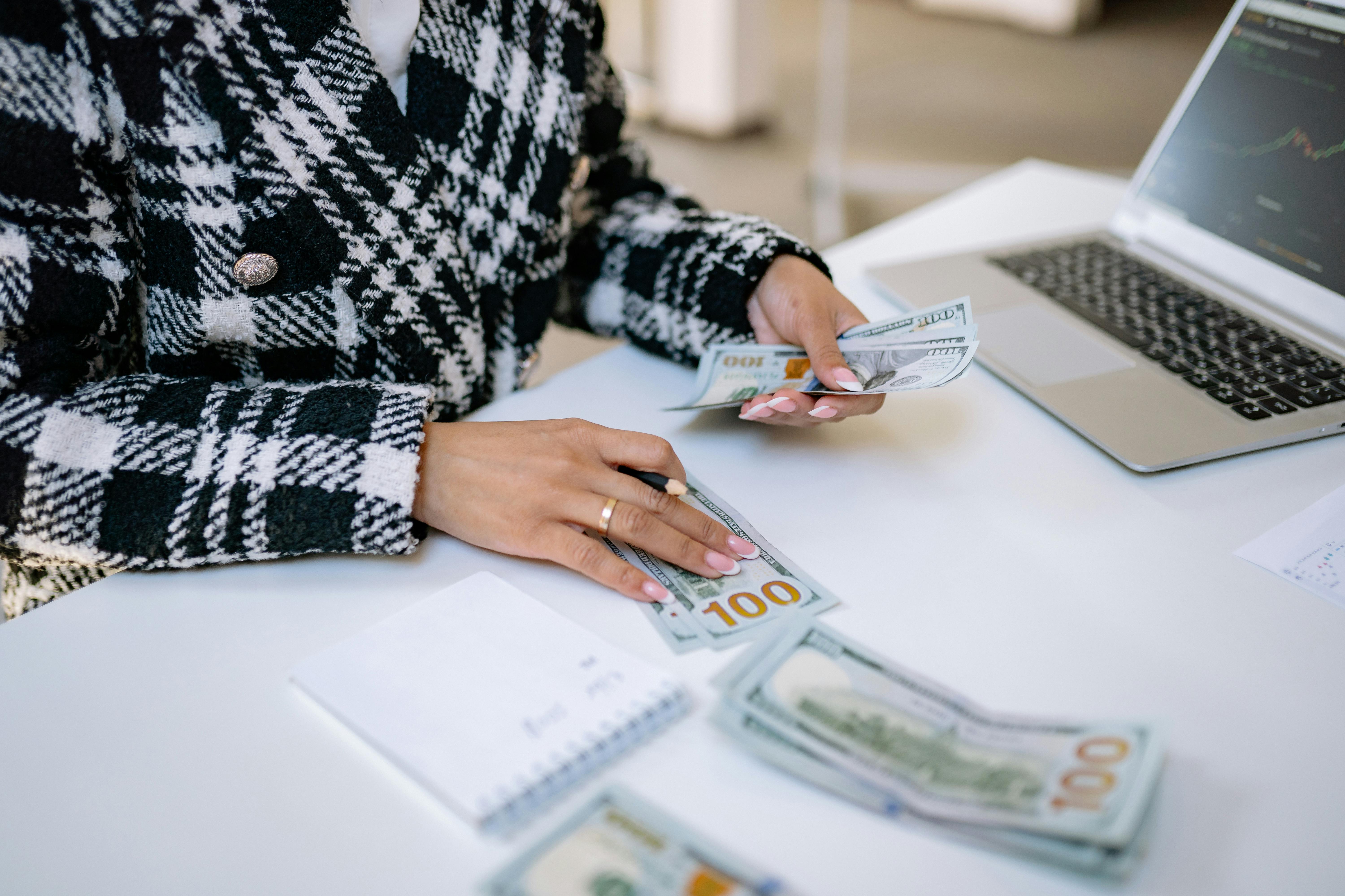A person sitting on the table counting money | Source: Pexels