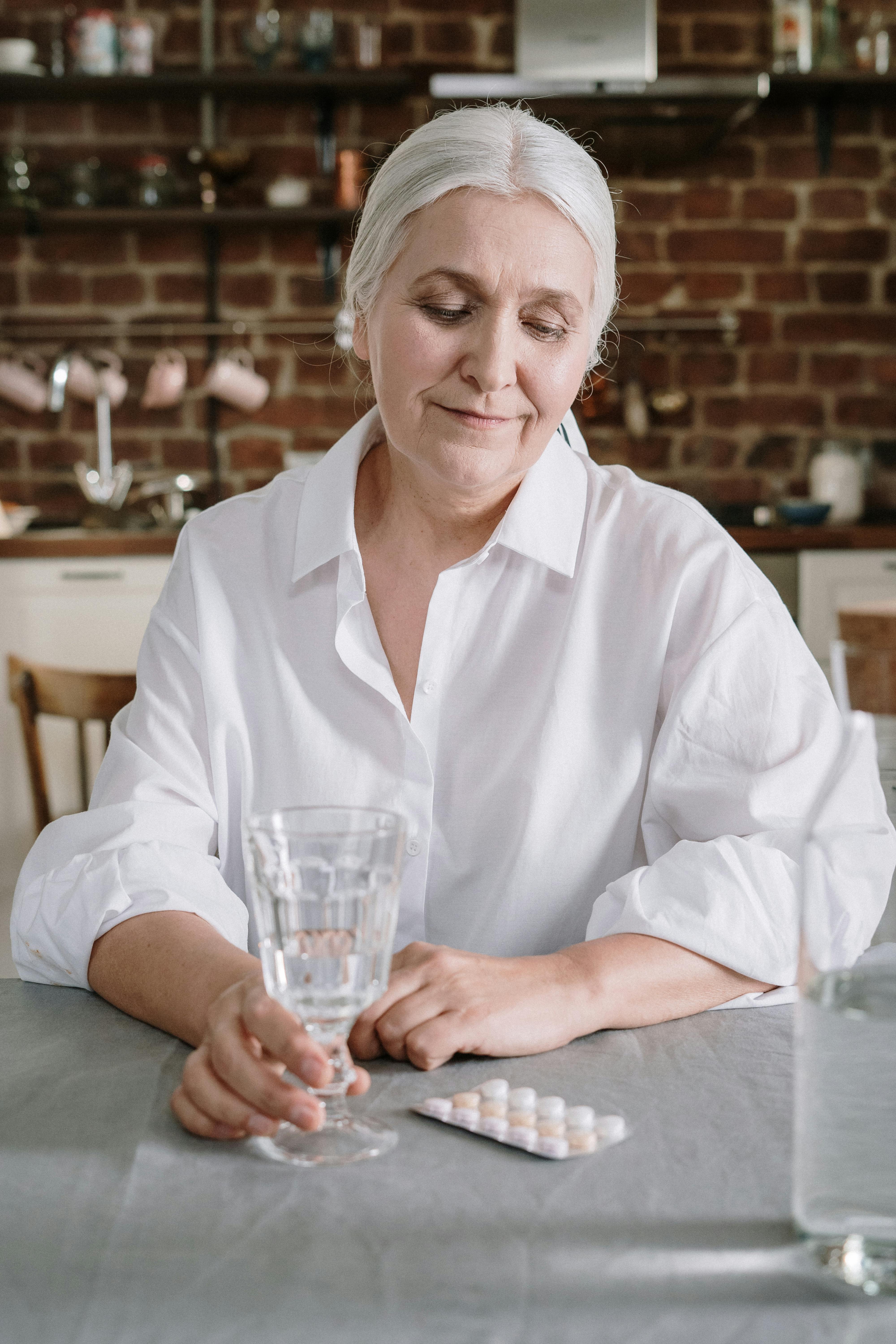 An older woman sitting at the table, looking at a set of medication | Source: Pexels