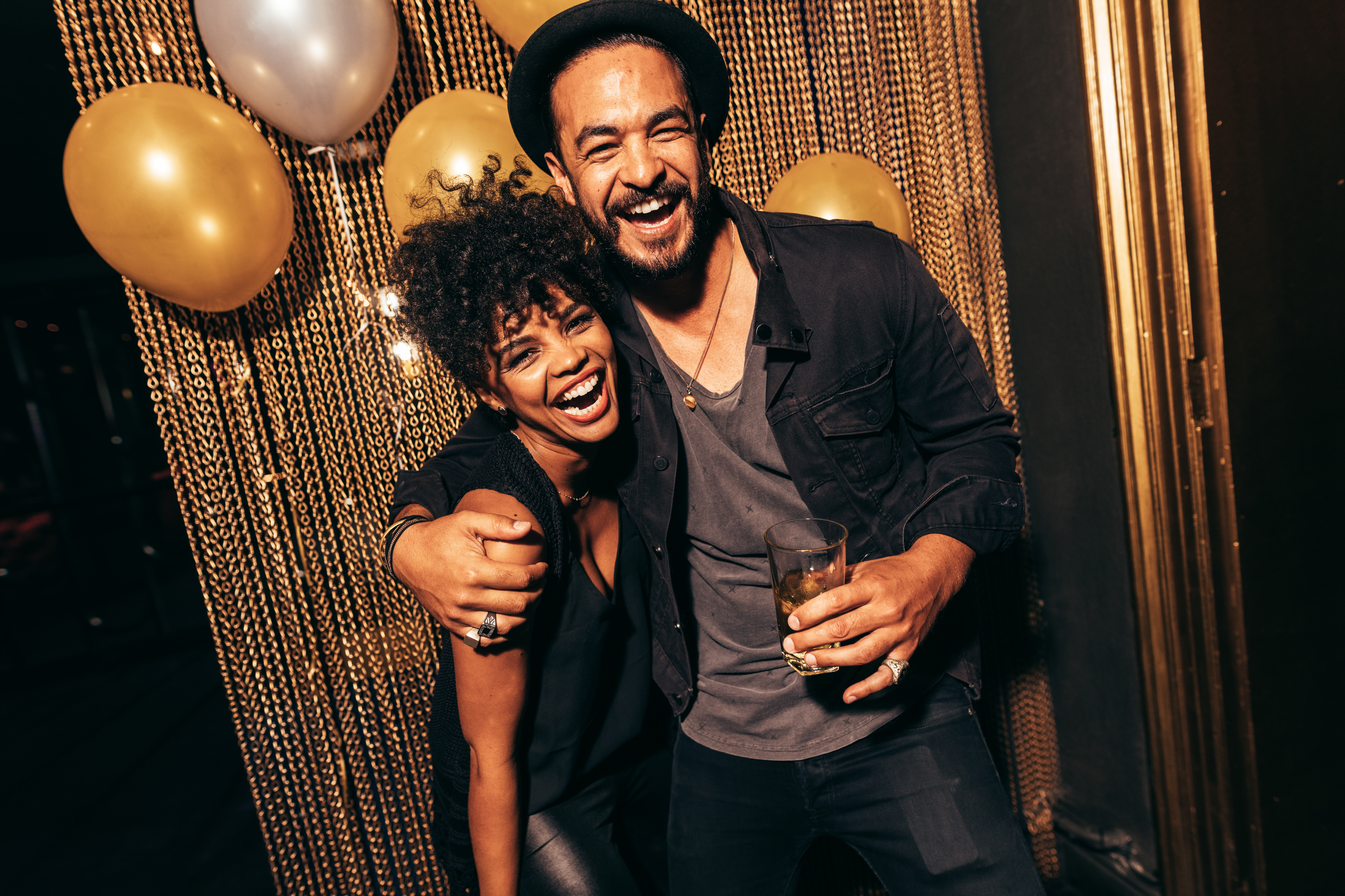 A young couple smiling for a photo at a party | Source: Shutterstock