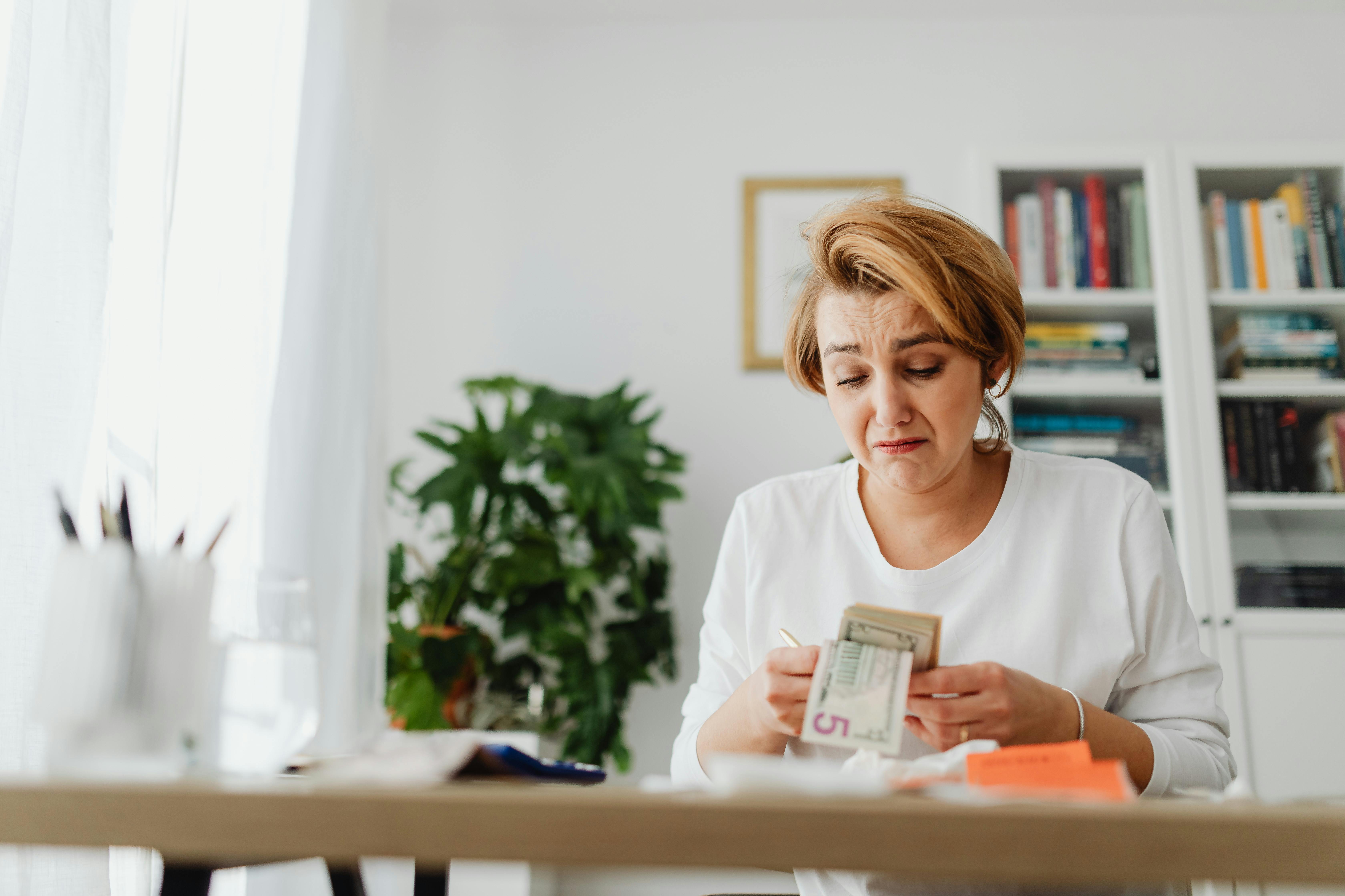 A sad woman counting money | Source: Pexels