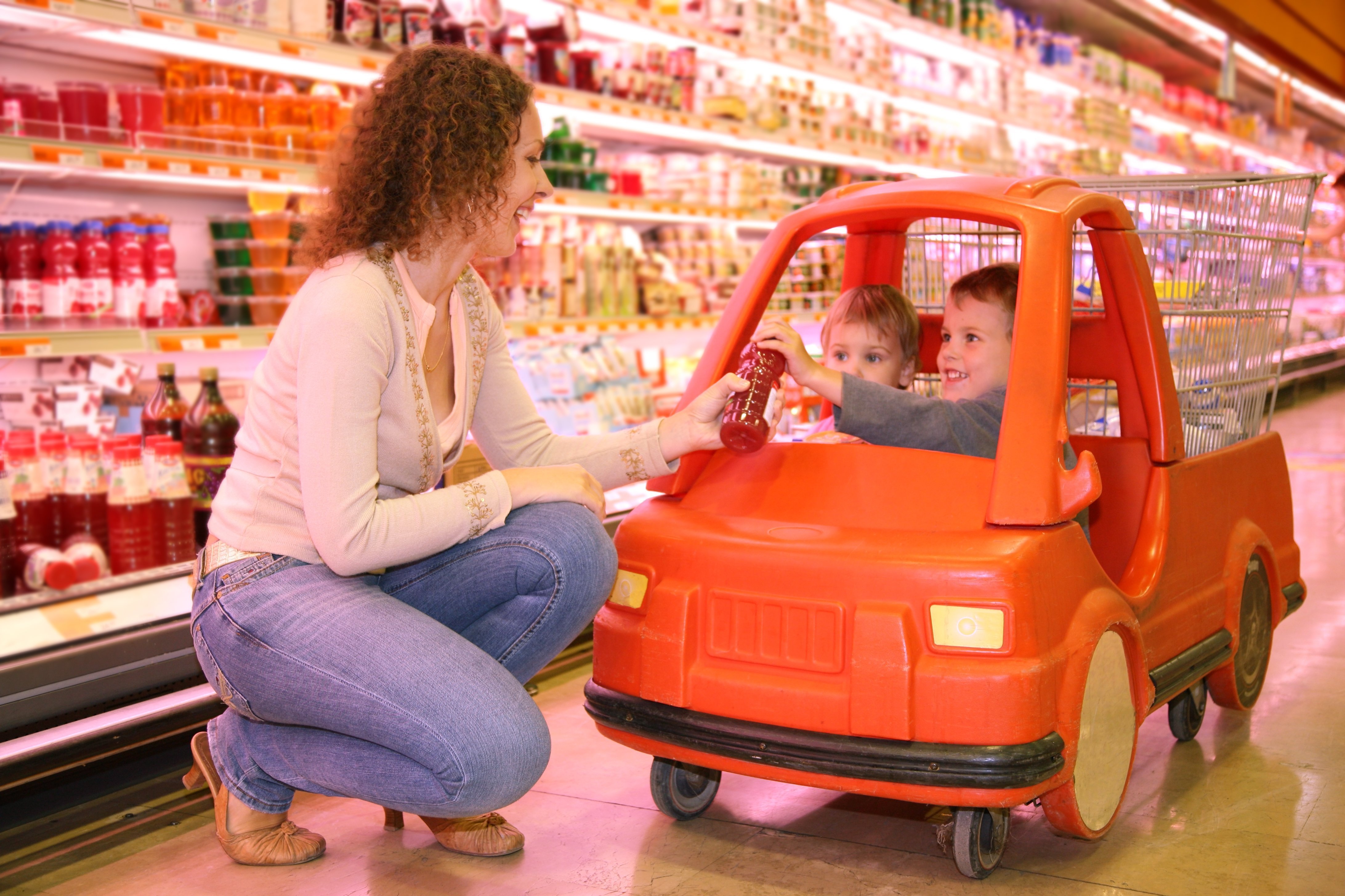 A woman handing a boy his fallen toy from the go-cart trolley. | Source: Shutterstock.