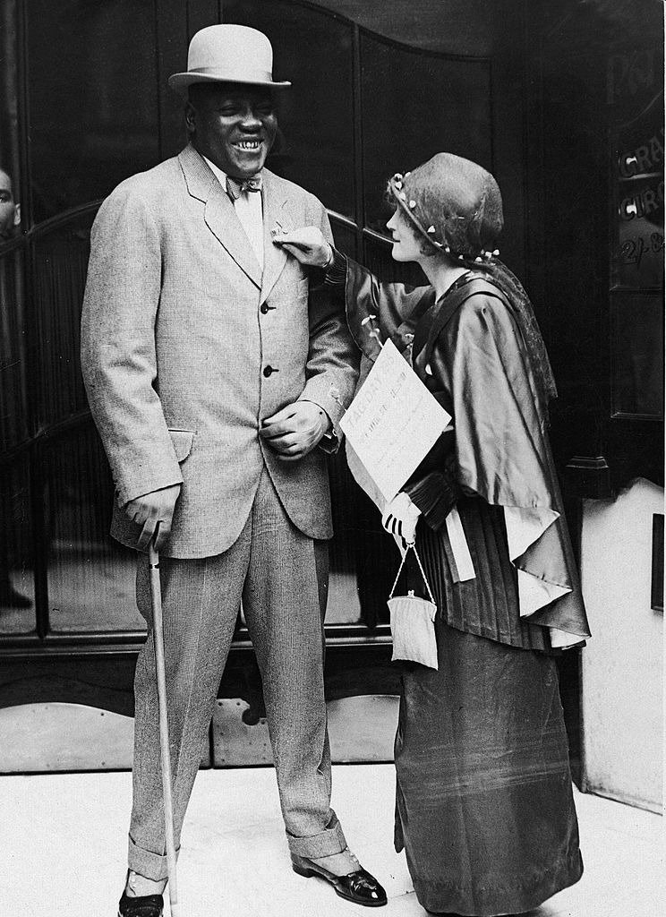 American boxer Jack Johnson, the world heavyweight champion, is tagged with a forget-me-not during a 'Tag Day' sales benefit of the flowers for the Music Hall Ladies Guild Orphanage, early 1910s  | Photo: Getty Images