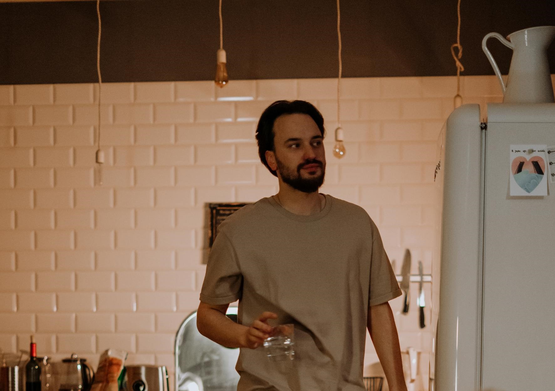 A man holding a glass of water in the kitchen | Source: Pexels