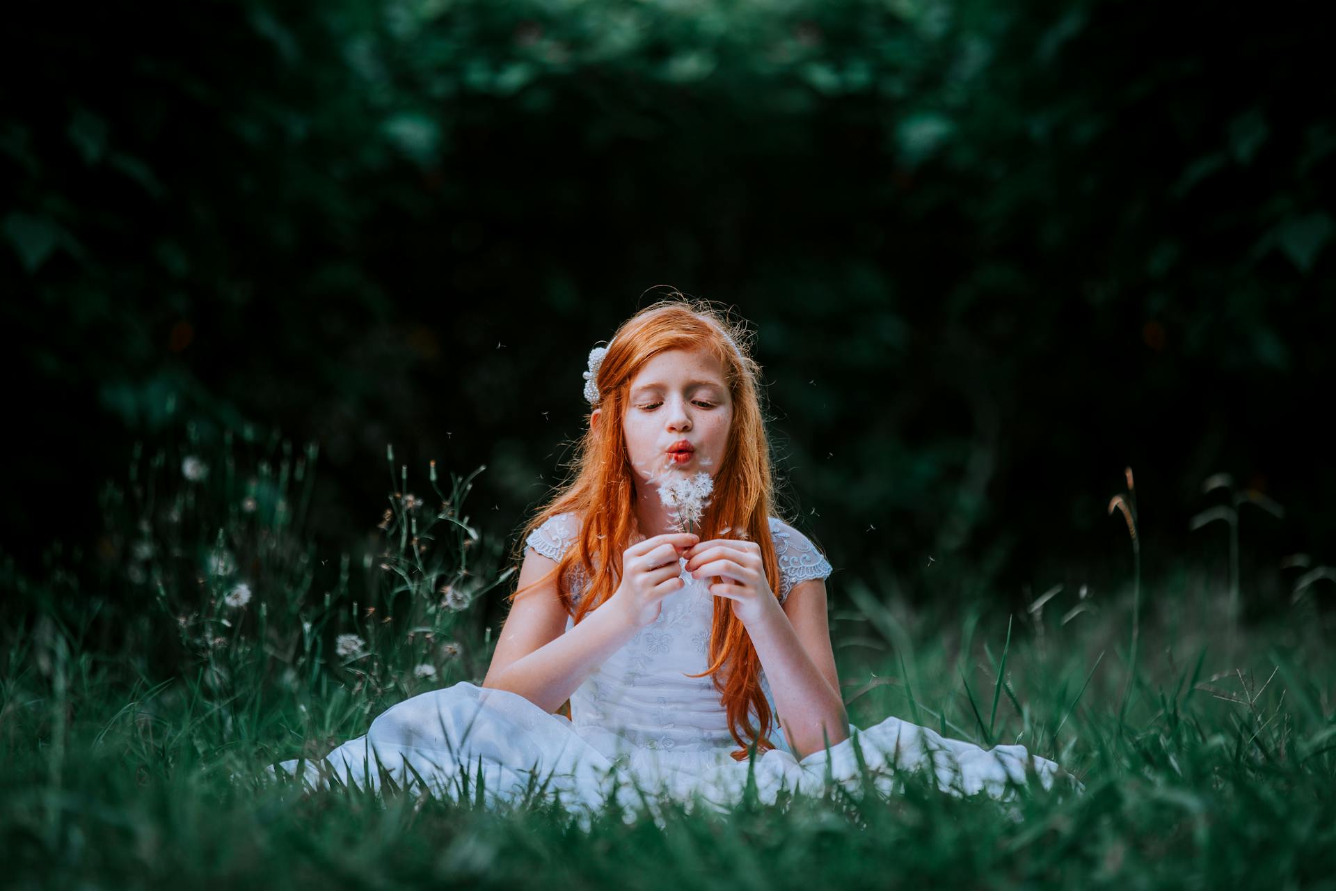 A little girl blowing dandelions | Source: Pexels