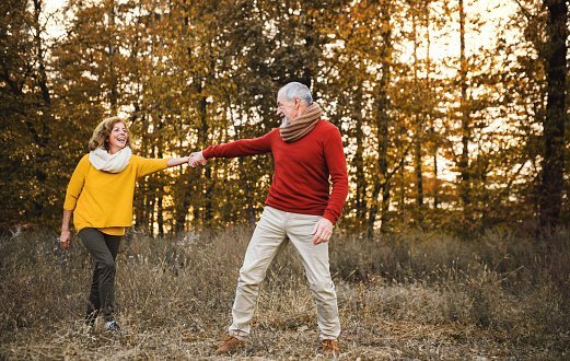 Photo of a senior couple on a walk in an autumn nature at sunset, holding hands. | Photo: Getty Images