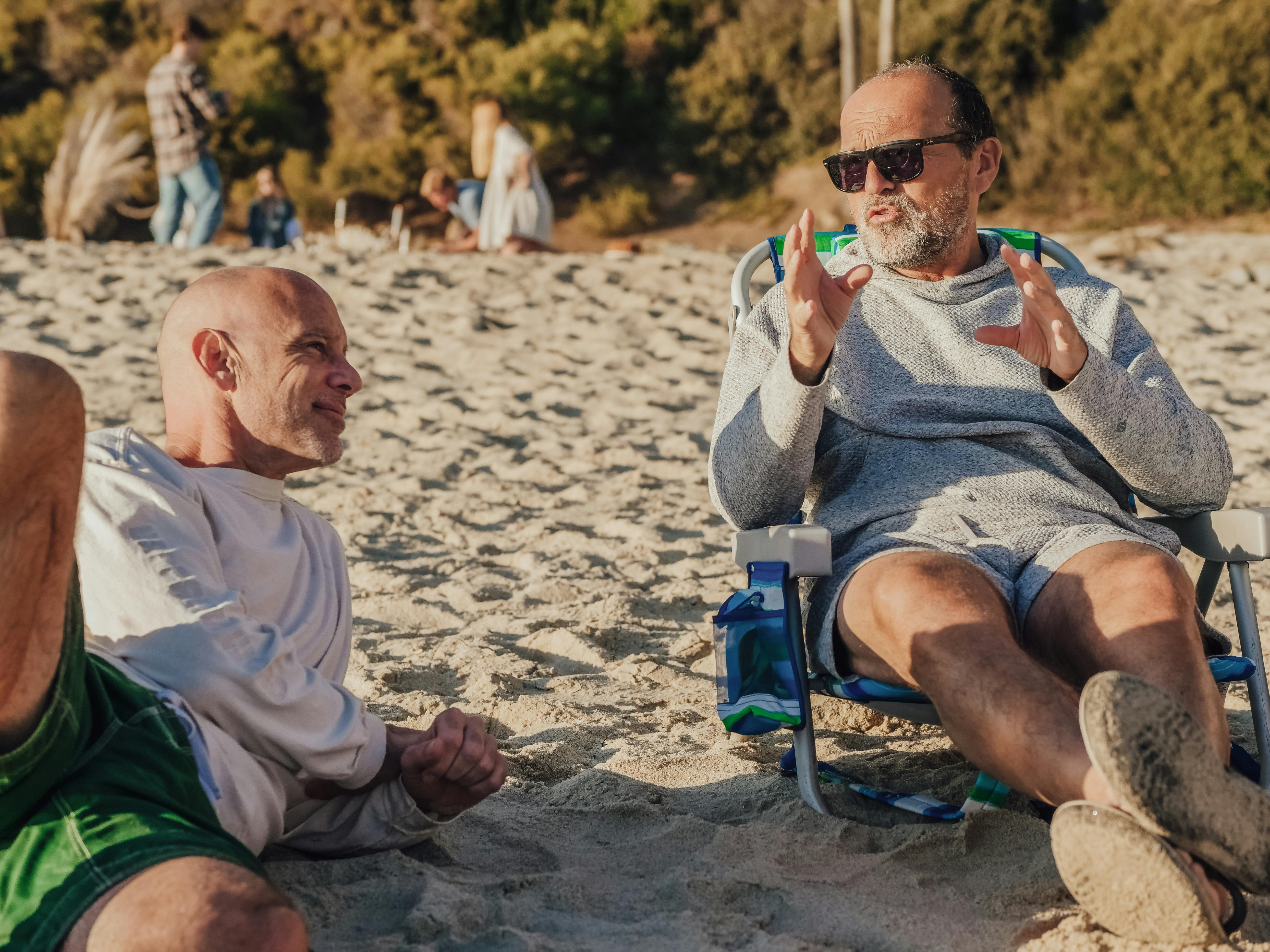 A middle-aged man boasting about something to another man at the beach | Source: Pexels