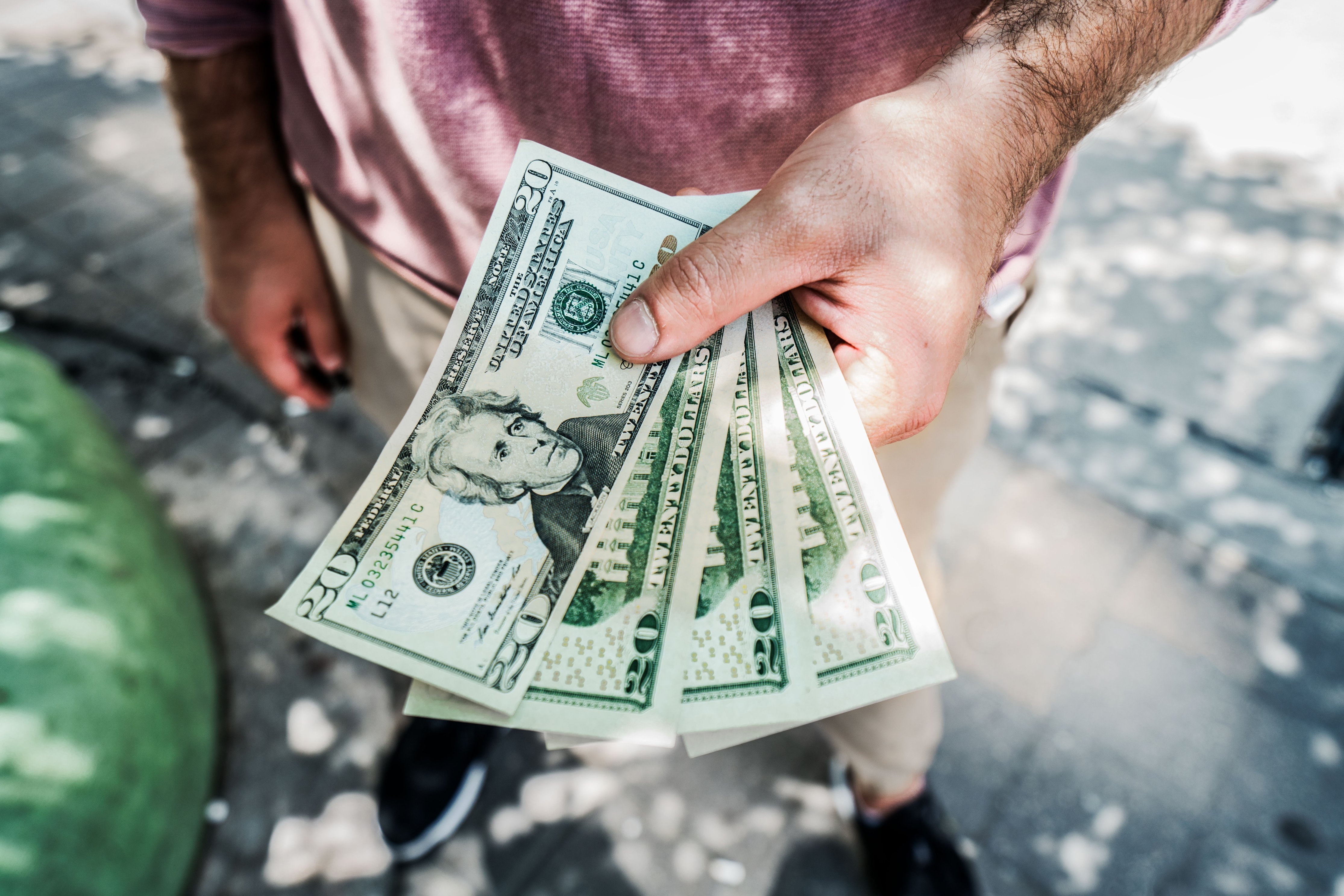 Mann hält 20-Dollar-Scheine in die Höhe. | Quelle: Pexels