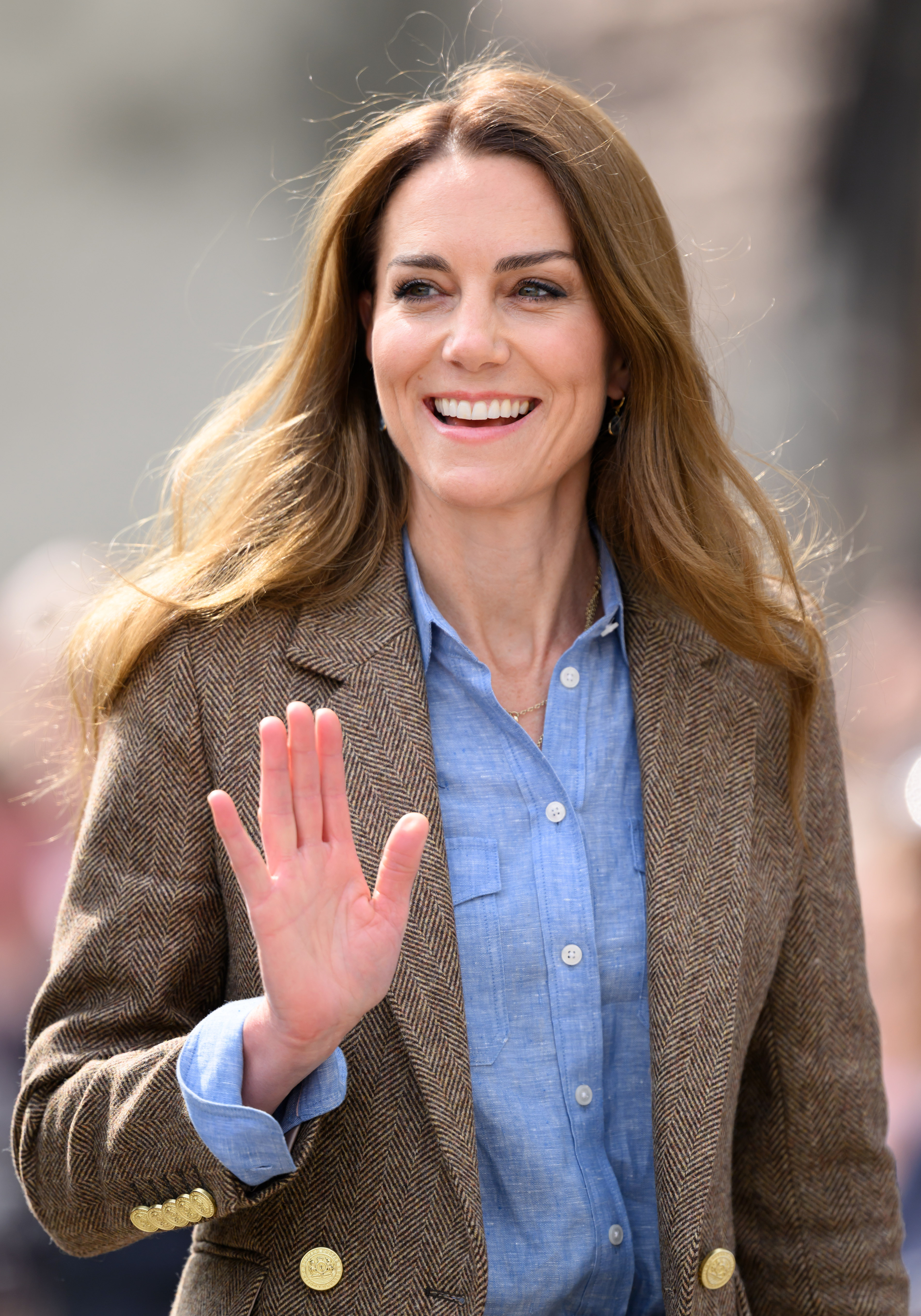 Catherine offers a cheerful wave to well-wishers lining the streets outside Aros Hall. Dressed in a brown herringbone blazer and chambray shirt, she greeted residents of Tobermory as part of the couple's ongoing outreach to island communities.