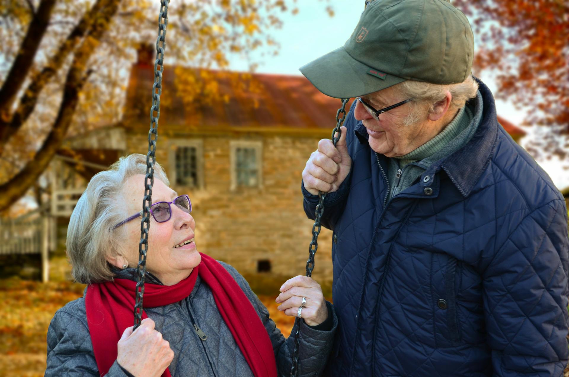An elderly man standing beside his wife on a swing | Source: Pexels