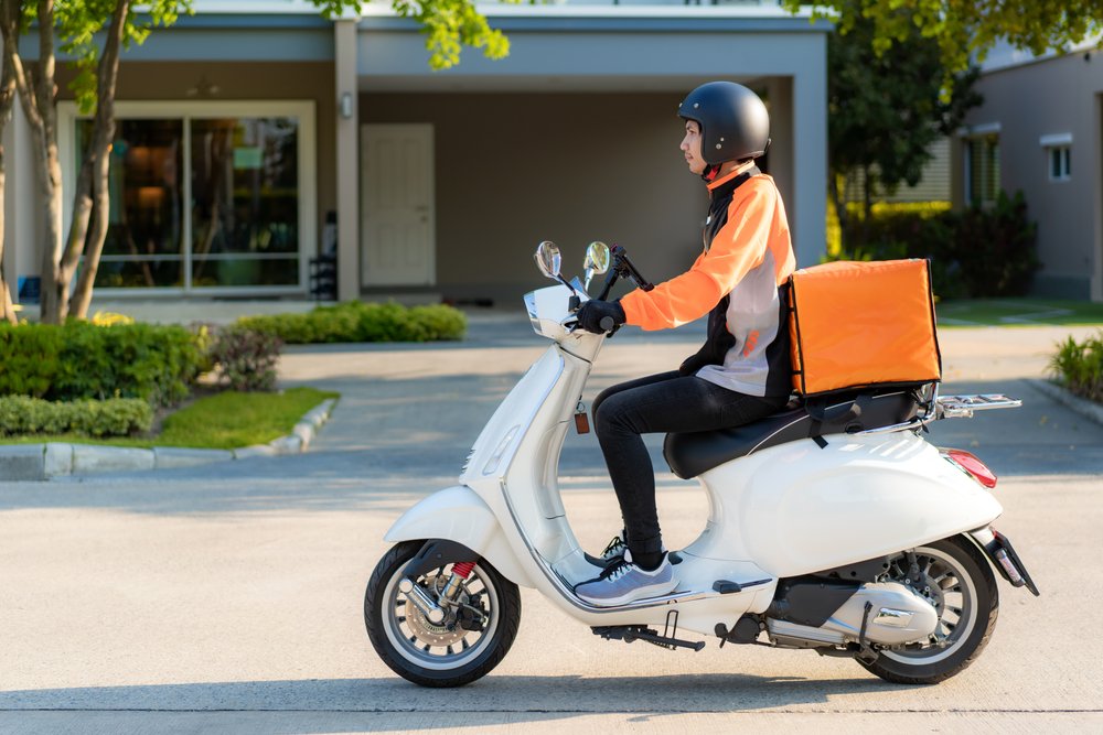 Joven trasladándose en una motocicleta para hacer la entrega de un pedido. | Foto: Shutterstock