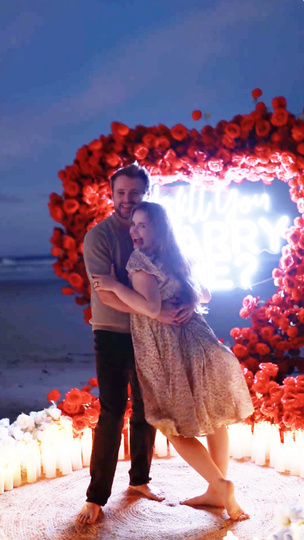 Jason Duggar and Maddie Grace hug in front of the heart-shaped neon backdrop on the beach, as seen in a video dated August 30, 2024 | Source: Instagram/kaylajohnsonphoto_