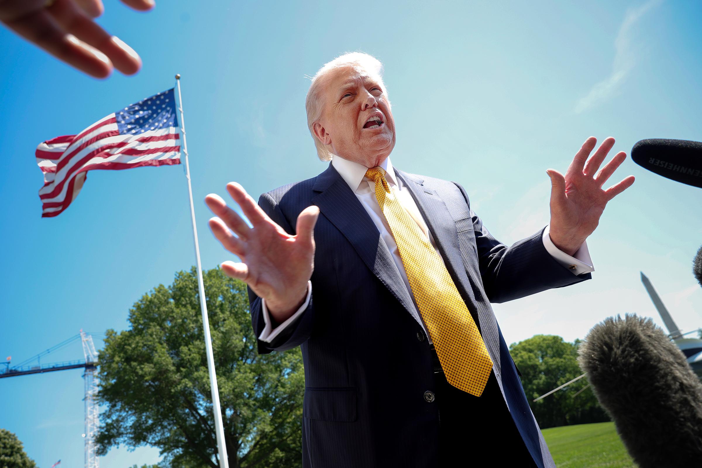 Donald Trump speaks in front of the American flag to the press as he departs the White House on May 12, 2026 in Washington, DC | Source: Getty Images