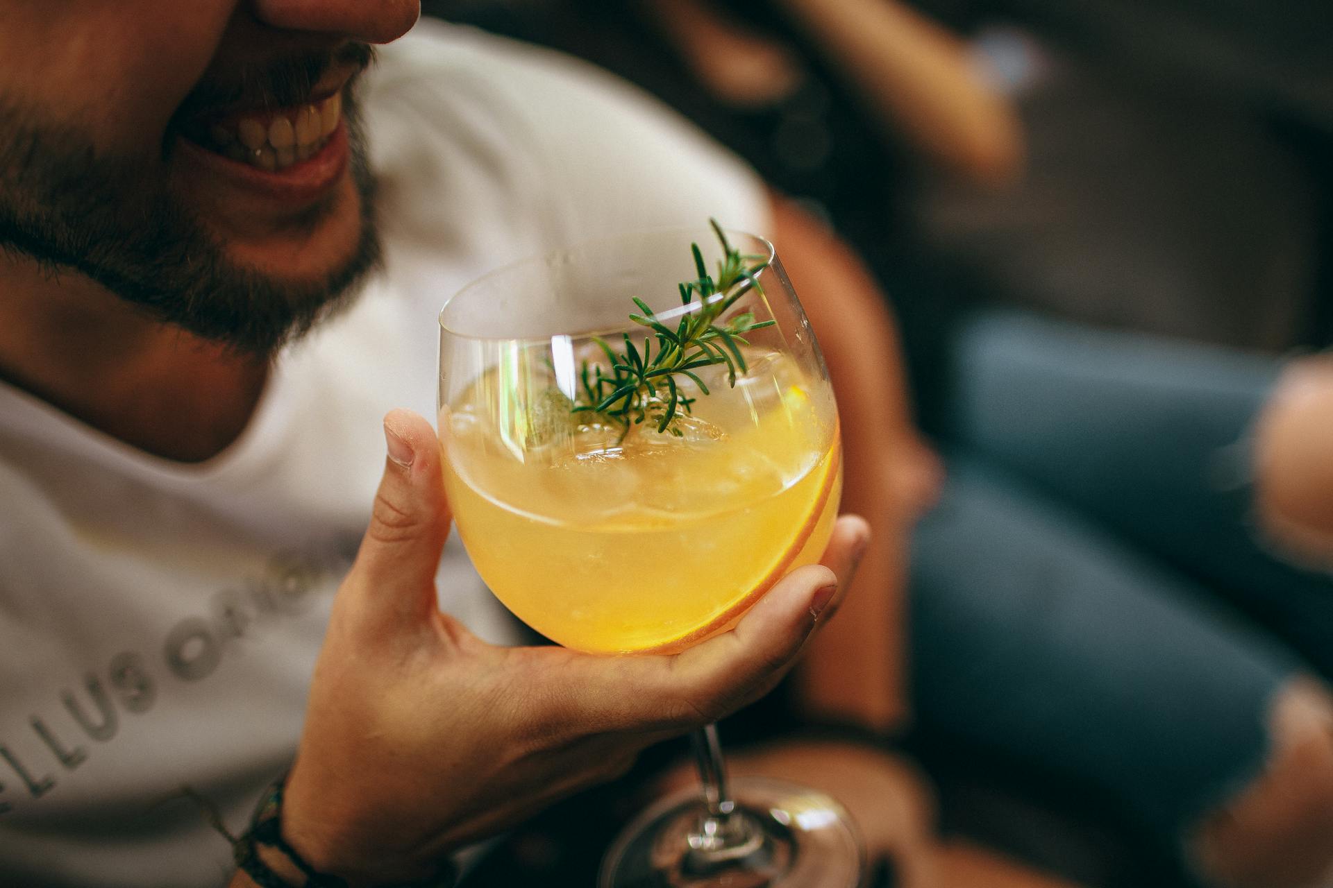A grinning man holding a drink | Source: Pexels