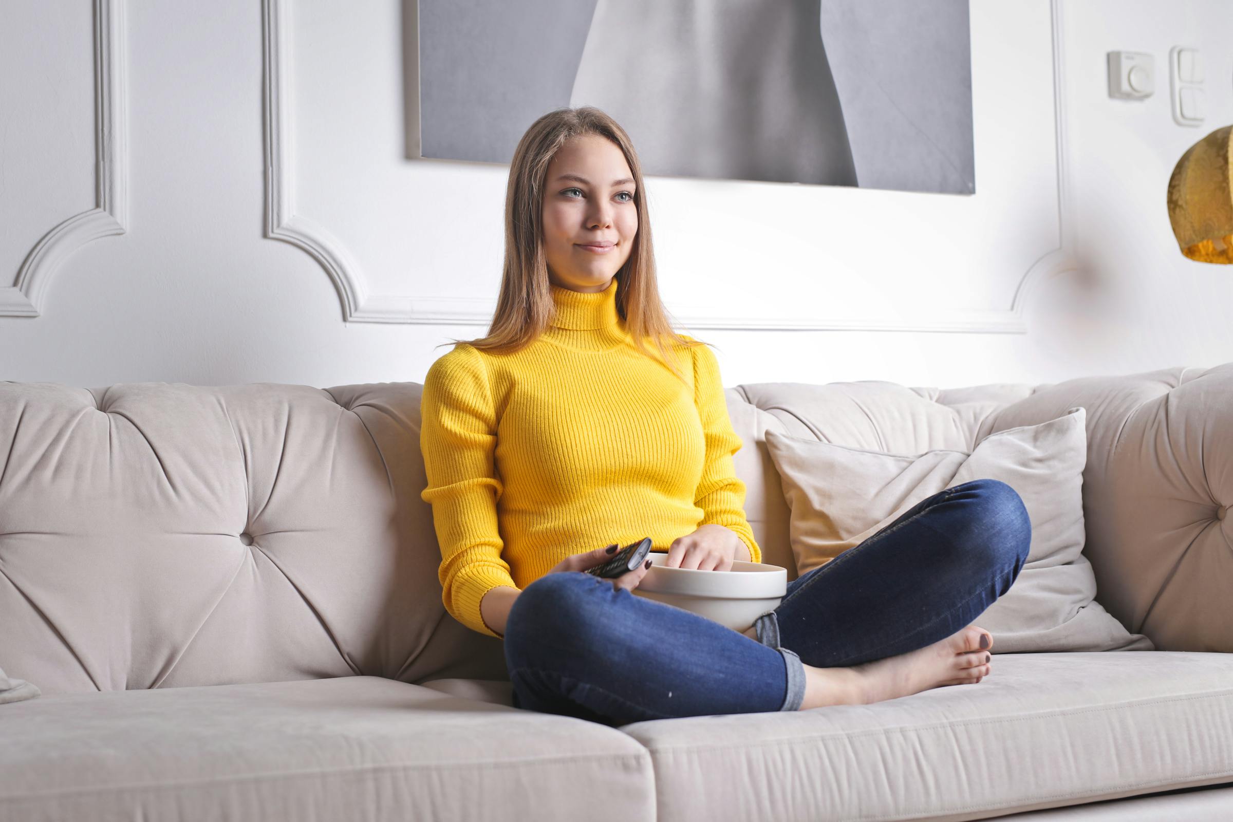 Woman sitting on a couch with popcorn | Source: Pexels