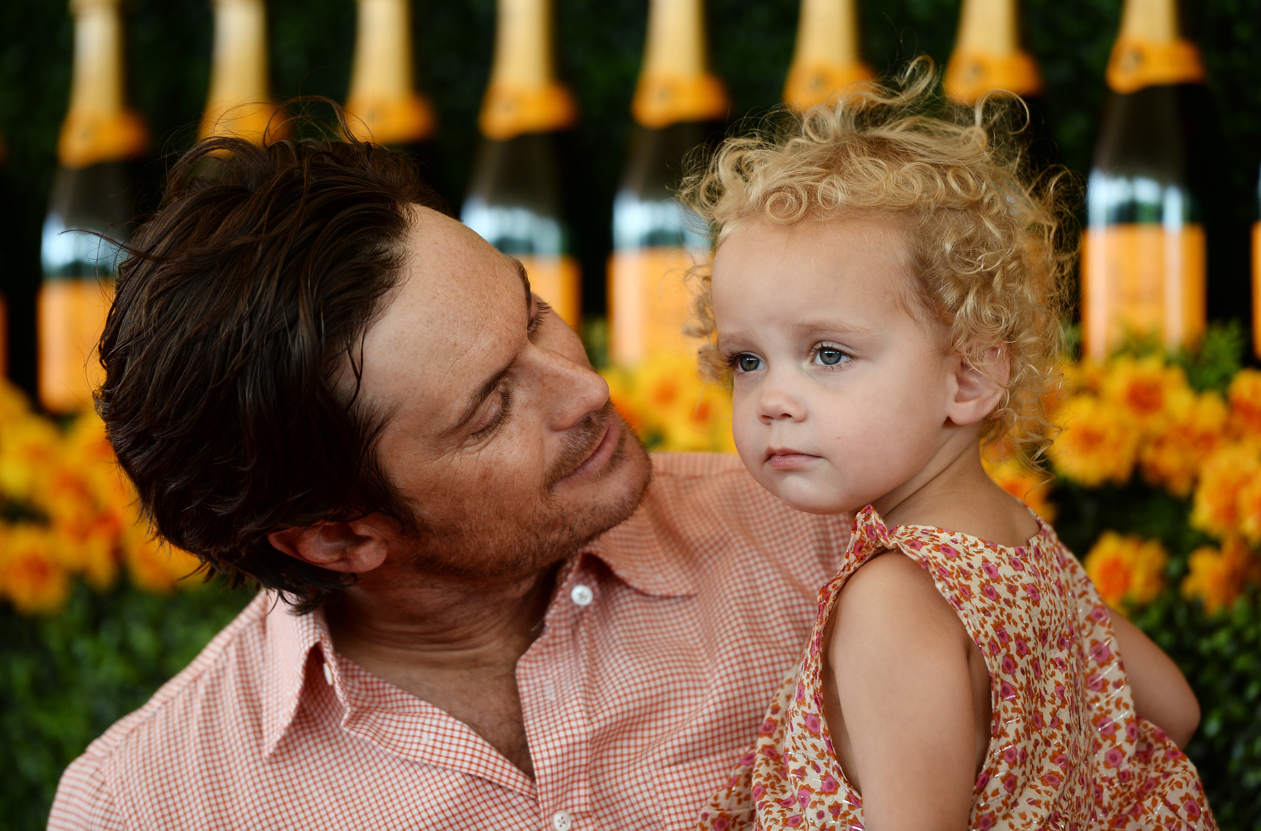 In this heartwarming moment from 2015, Oliver Hudson cradles his young daughter Rio at the Veuve Clicquot Polo Classic. With a gentle smile and proud eyes, the actor poses on the red carpet, capturing a sweet father-daughter bond that charmed fans early on.