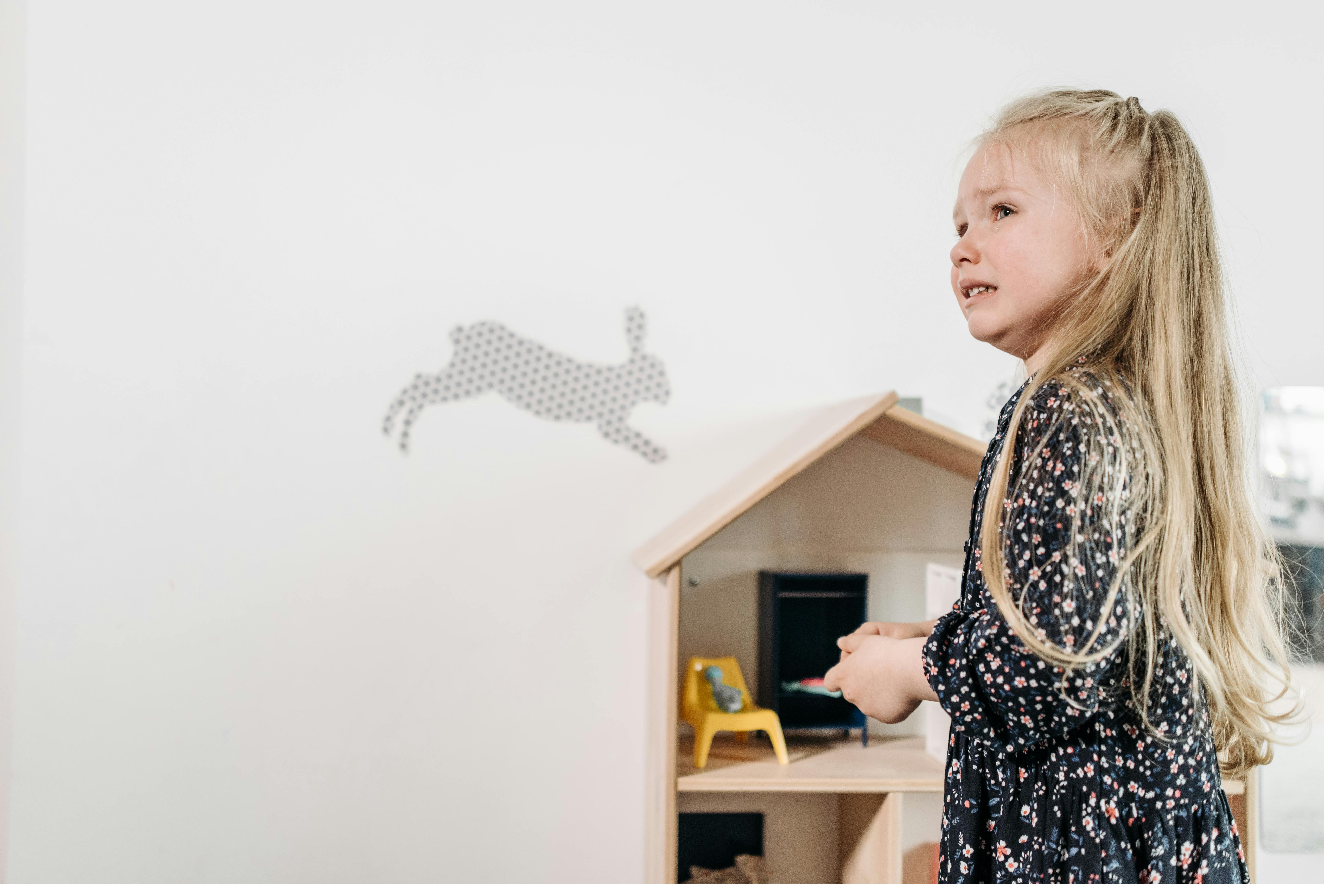 A crying girl and a doll house | Source: Pexels