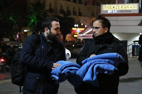 Huseyin Yurtseven y un amigo cargando las mantas que usarán para cubrir perros y gatos callejeros en Estambul, Turquía. | Foto: Getty Images