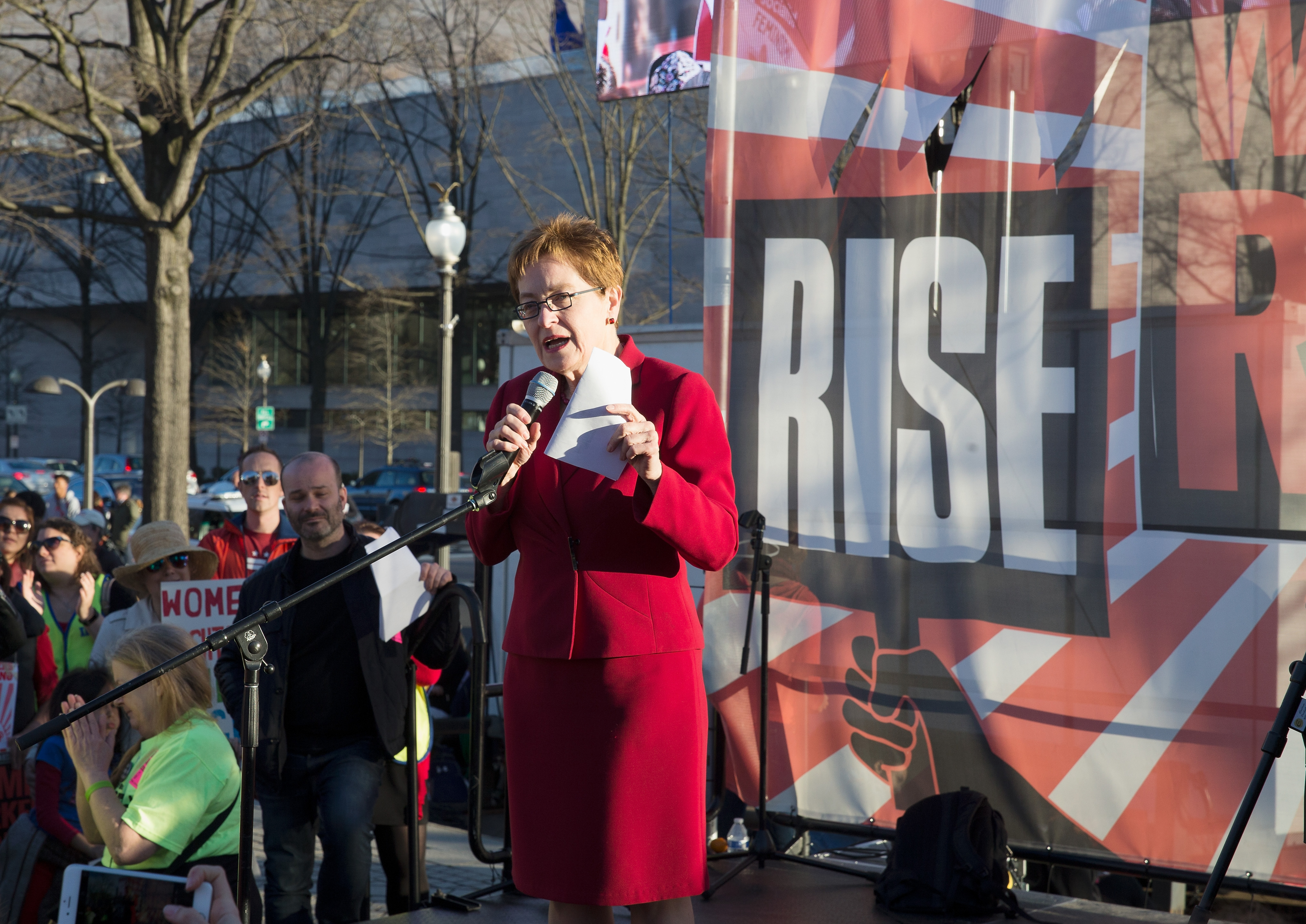 Speaking before a "RISE" banner at a community rally, the record-breaking lawmaker embodies the resilience her supporters expect as she recovers from her hospital stay to tackle her upcoming reelection fight. | Source: Getty Images