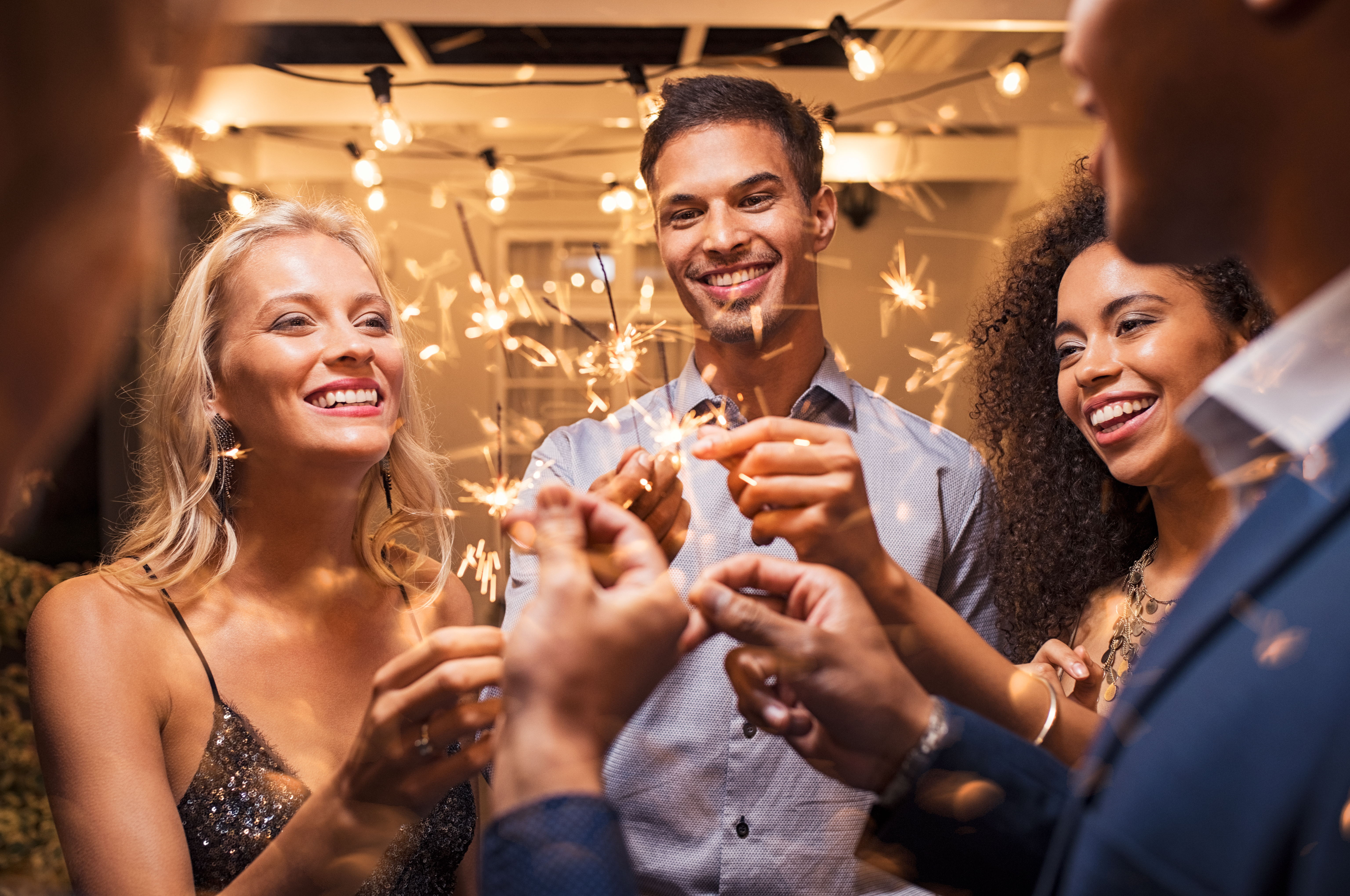 A group of young men and women are seen holding sparklers and celebrating the New Year. | Source: Shutterstock